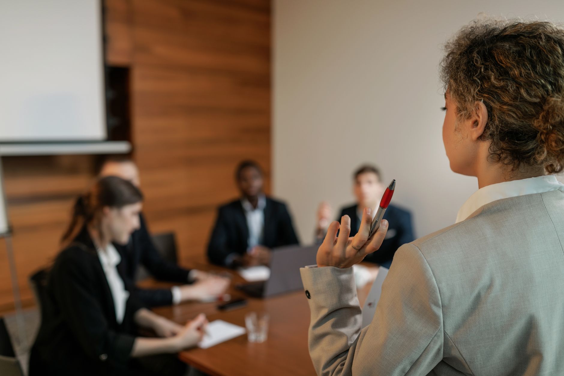 Qualifi Level 3 Integrated Diploma in Business and Management — Professional team engaging in a business meeting with focus on presenter holding a pen.