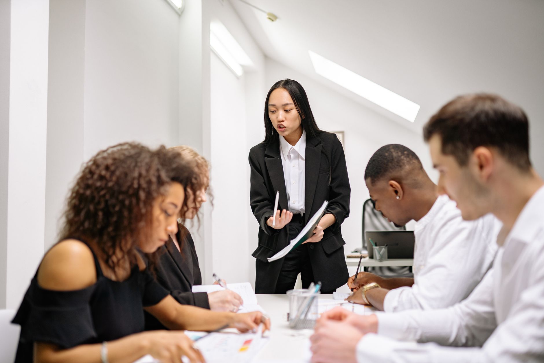 Qualifi Level 7 Diploma in Ethical Leadership — A diverse group of business people collaborating in an office meeting, led by a woman.