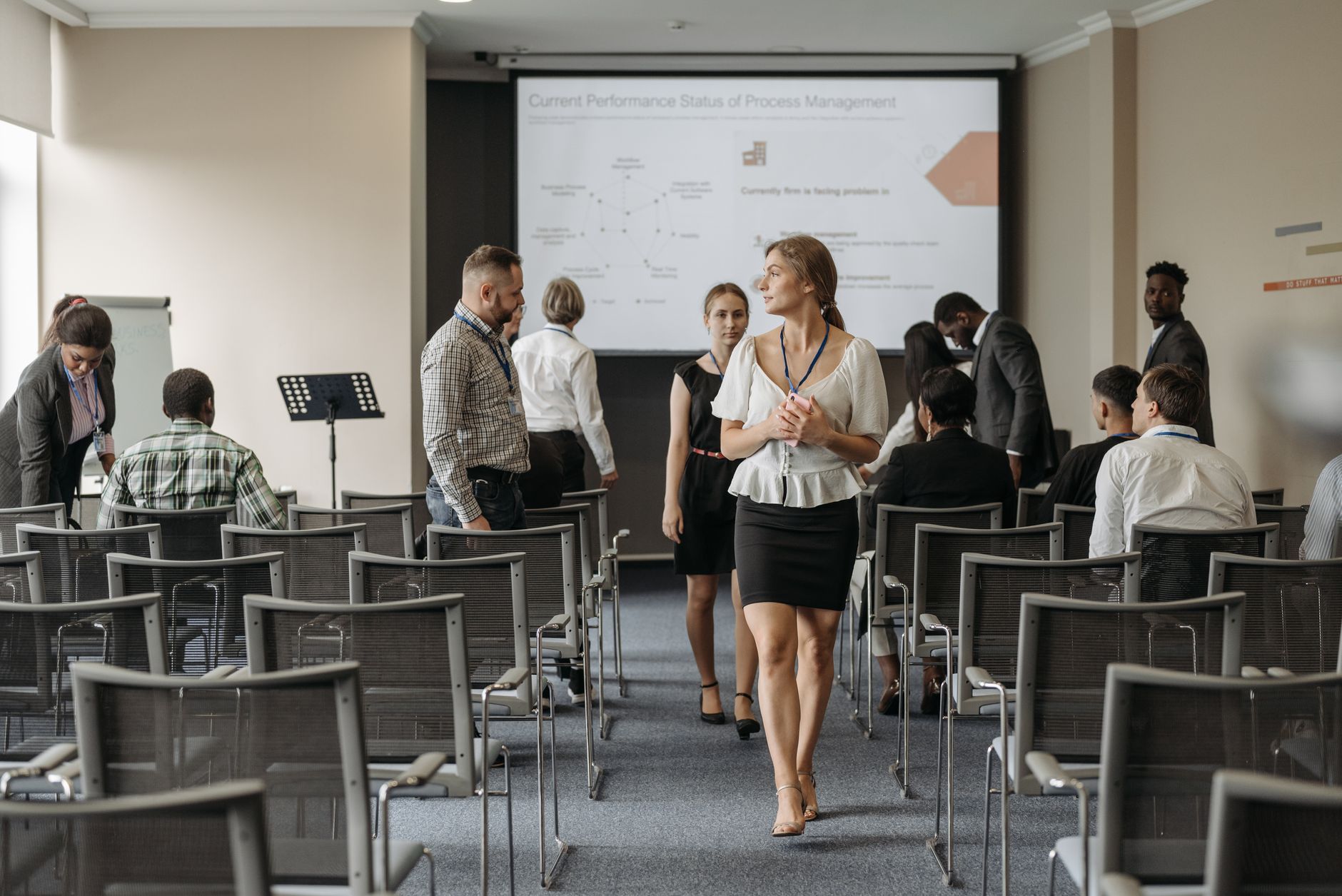 Qualifi Level 7 Diploma in Project Management — Professionals at a business conference engage before a presentation in a modern office.