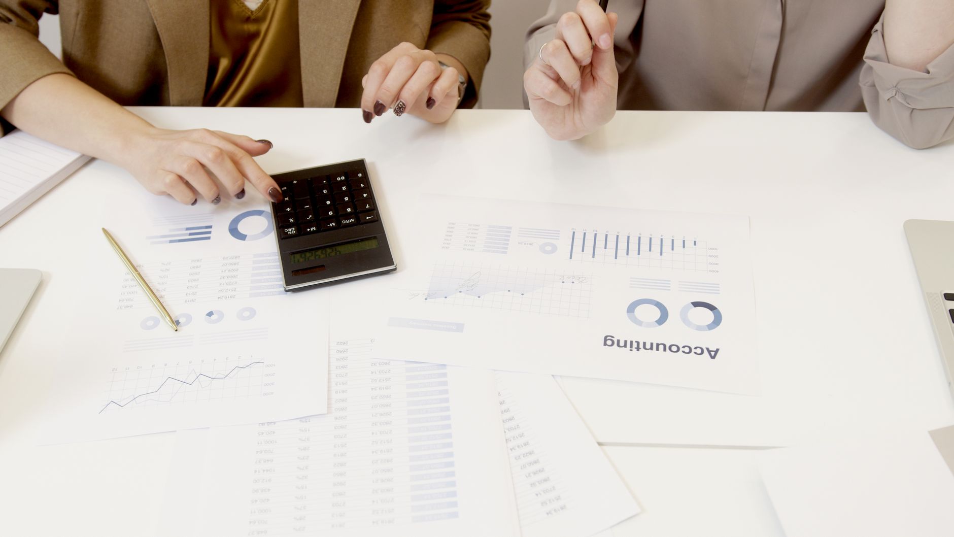 Qualifi Level 7 Diploma in Risk Management — Two professionals analyzing financial documents with a calculator.