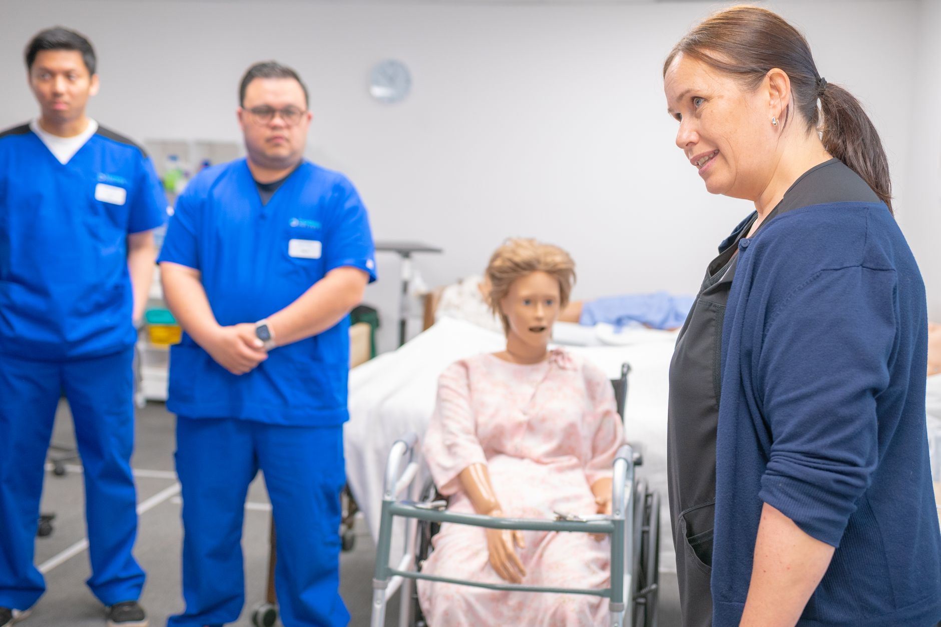 Qualifi Level 2 Diploma in Care — Nursing students and an instructor engage in a realistic clinical training using a medical mannequin.