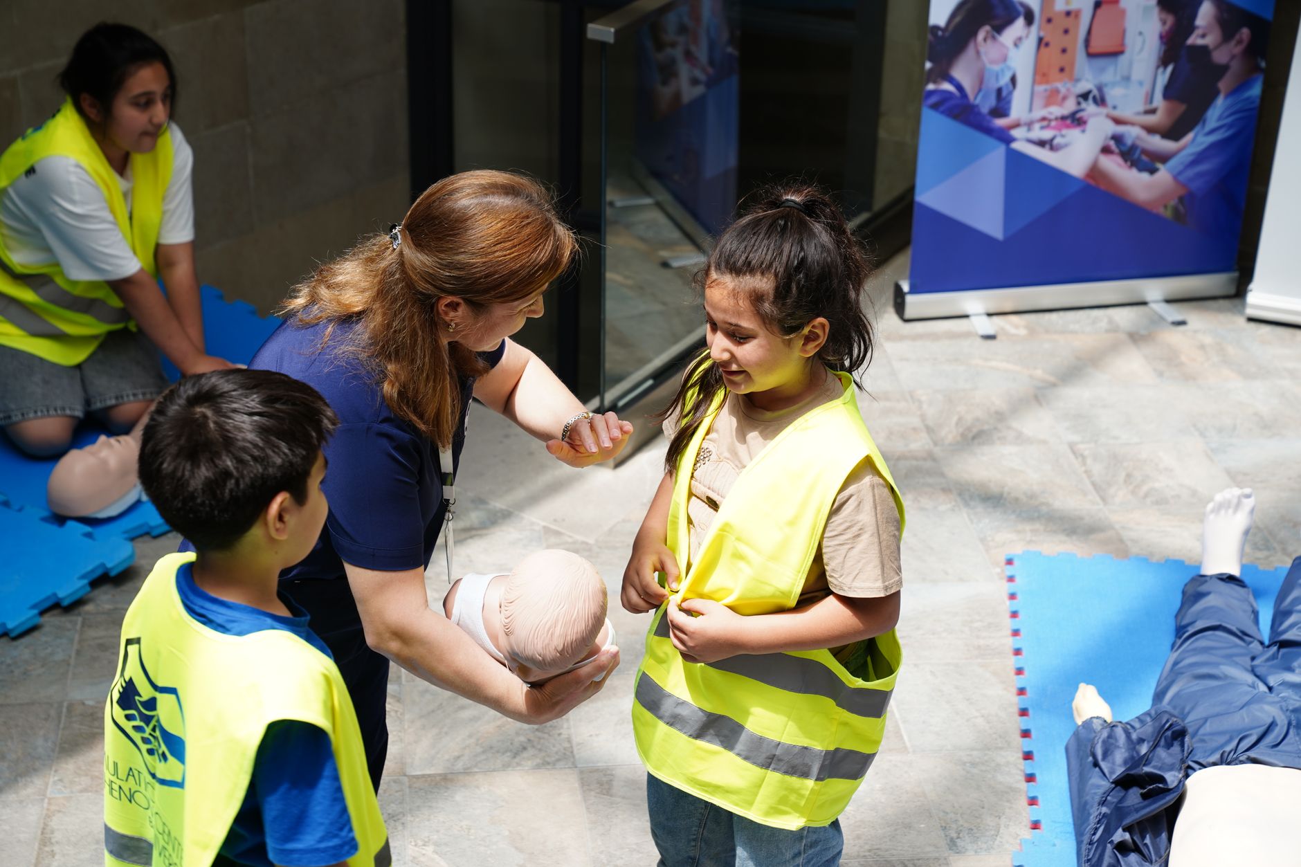 Qualifi Level 5 Diploma in Health and Social Care — Kids and instructor learning CPR techniques during first aid safety training.