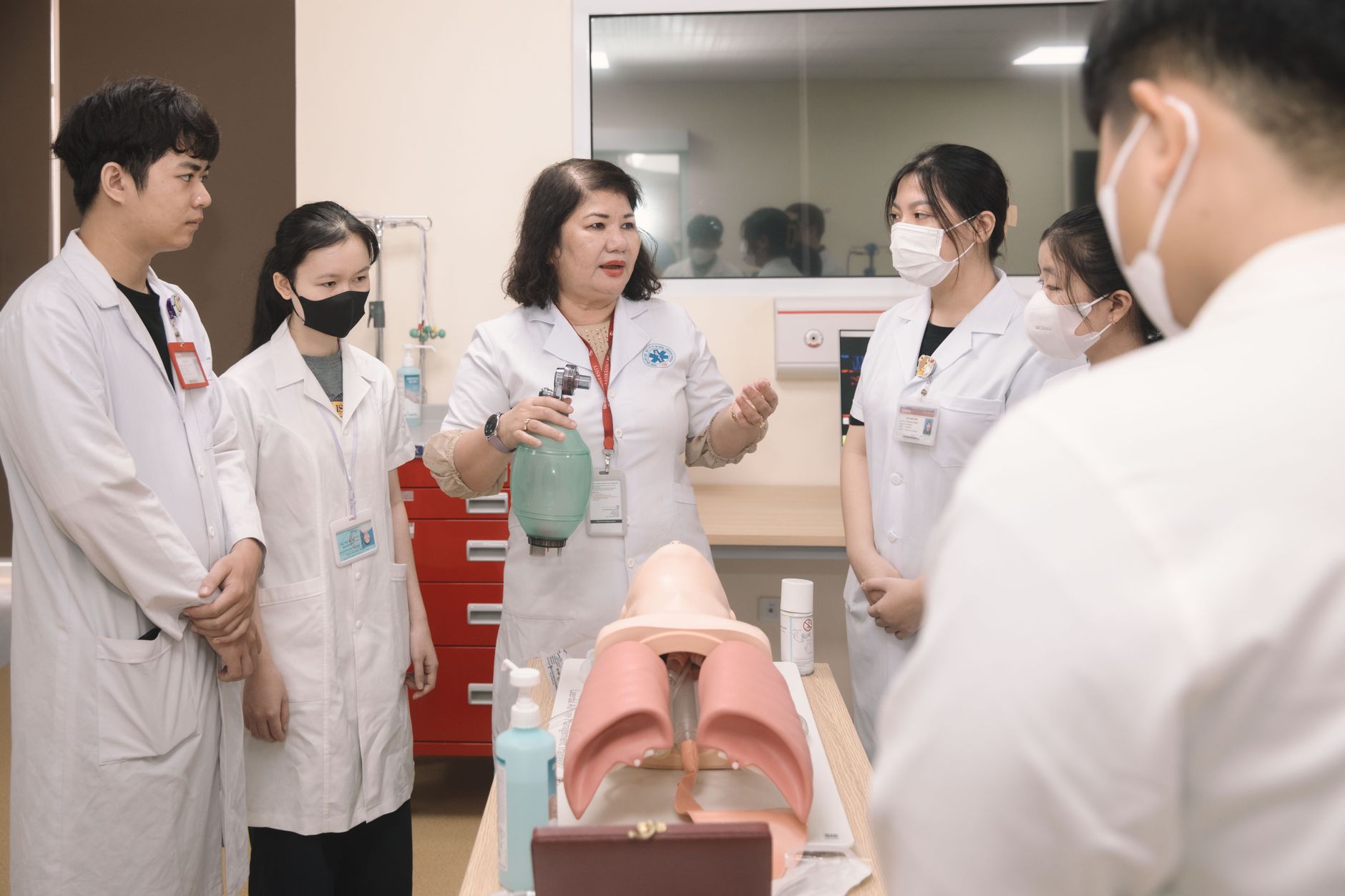 Qualifi Level 7 Diploma in Relational Practice in Mental Health — Group of medical students practicing skills with a training mannequin in a classroom setting.