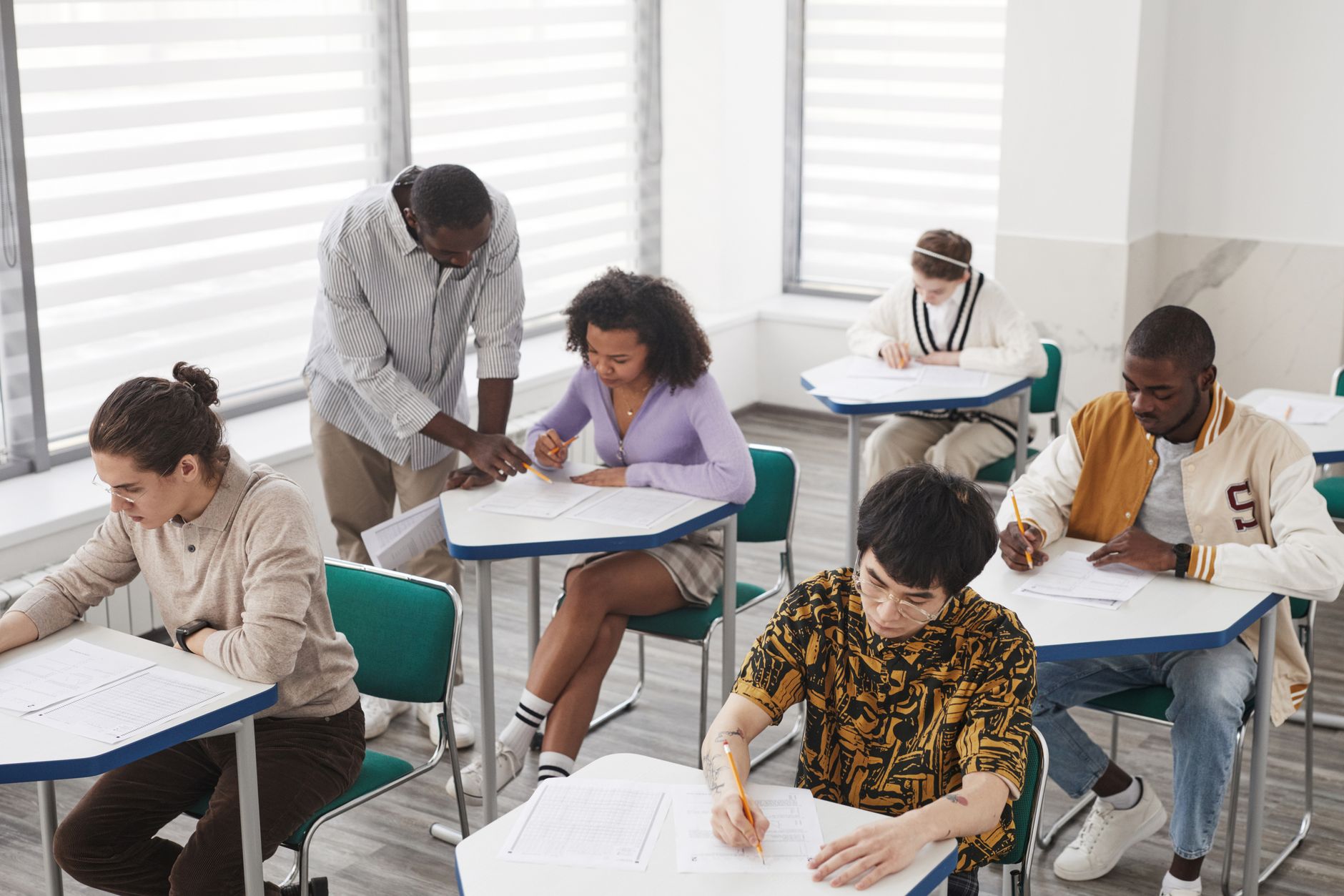 Qualifi Level 5 Diploma in Psychology — A diverse group of college students taking an exam, supervised by a teacher, in a classroom setting.