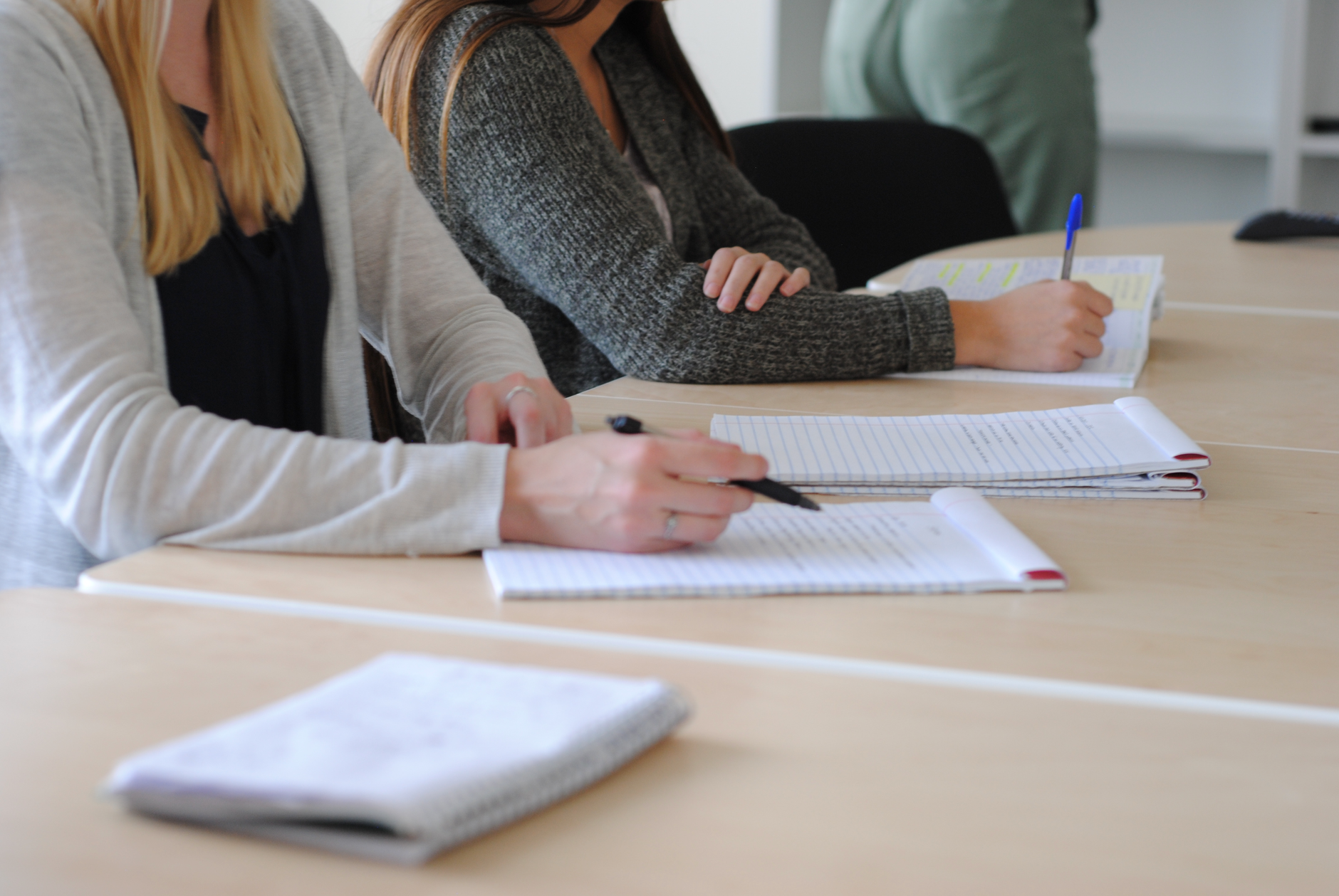 Qualifi Level 5 Extended Diploma in Psychology — Group of students writing notes at a meeting in a well-lit classroom.