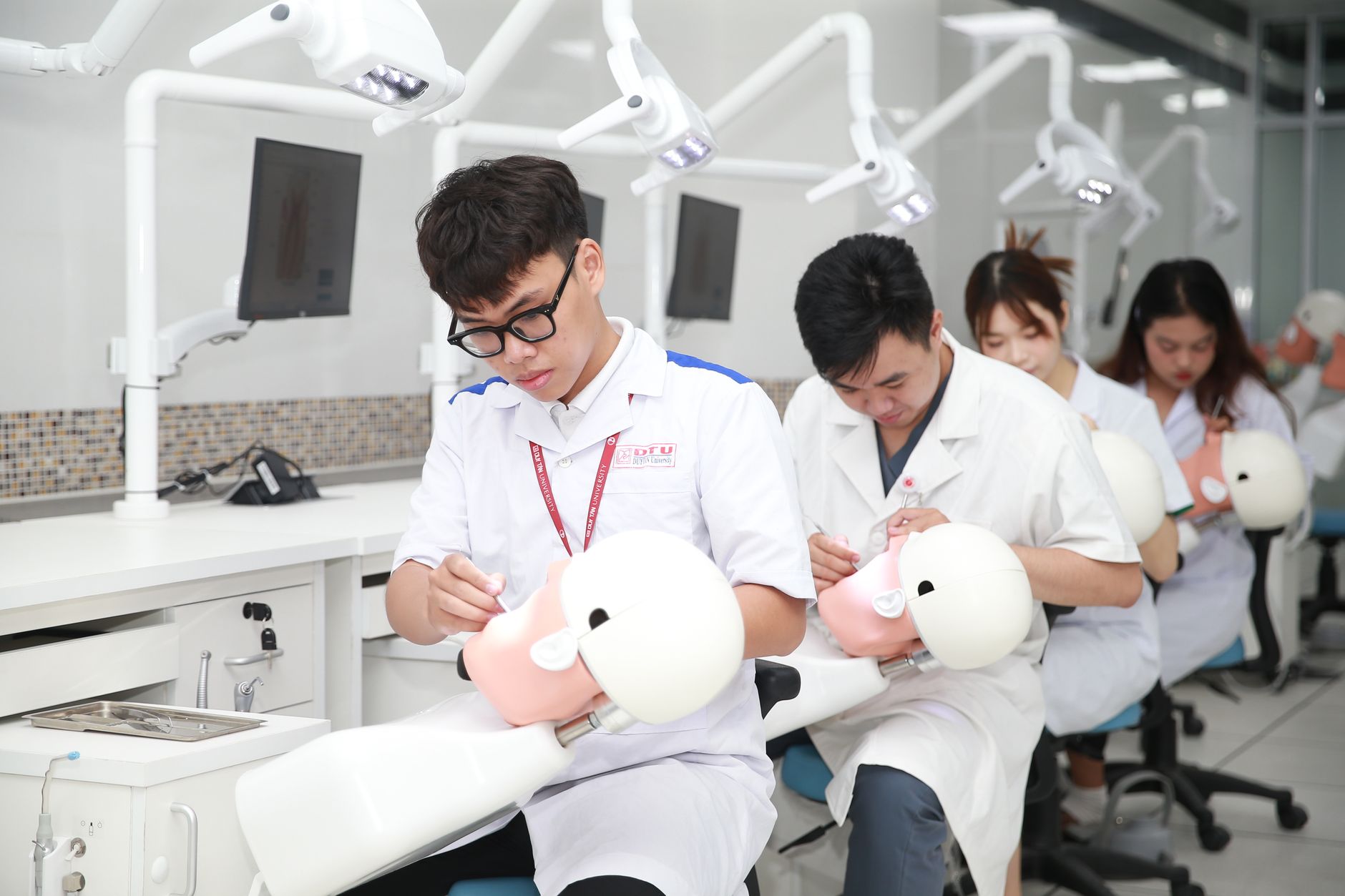 Qualifi Level 3 Extended Diploma in Hospitality and Tourism Management — Dental students in a training lab practicing on mannequin heads for skill development.