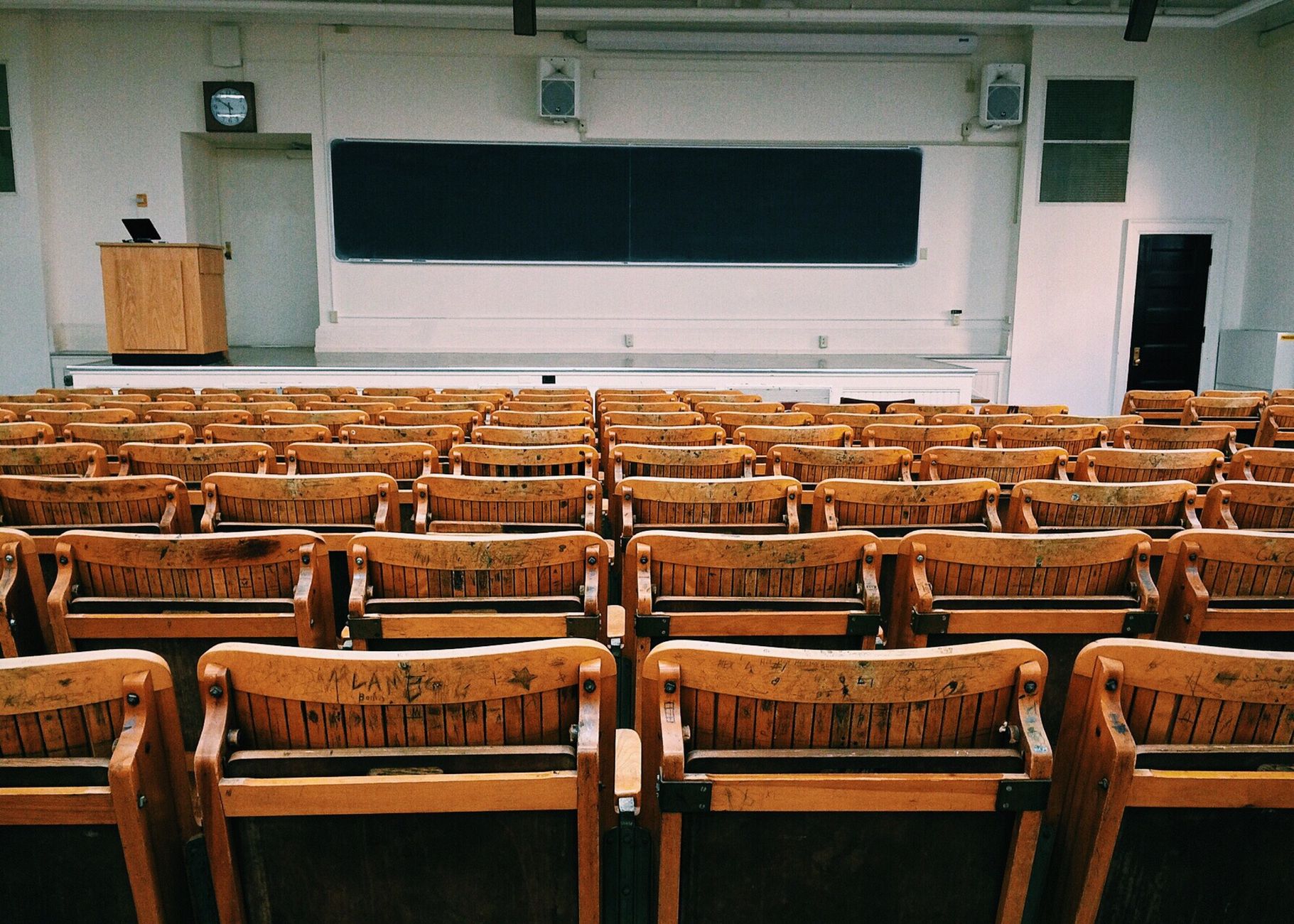 Qualifi Level 3 Diploma in Law — An empty lecture hall featuring wooden chairs and a large blackboard.