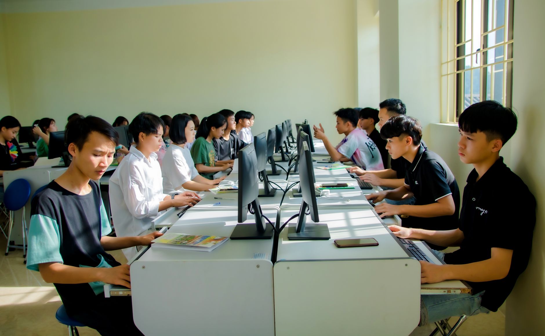 Qualifi Level 3 Extended Diploma in IT and Data Science — A group of students focused on computer tasks in a classroom setting, fostering teamwork.