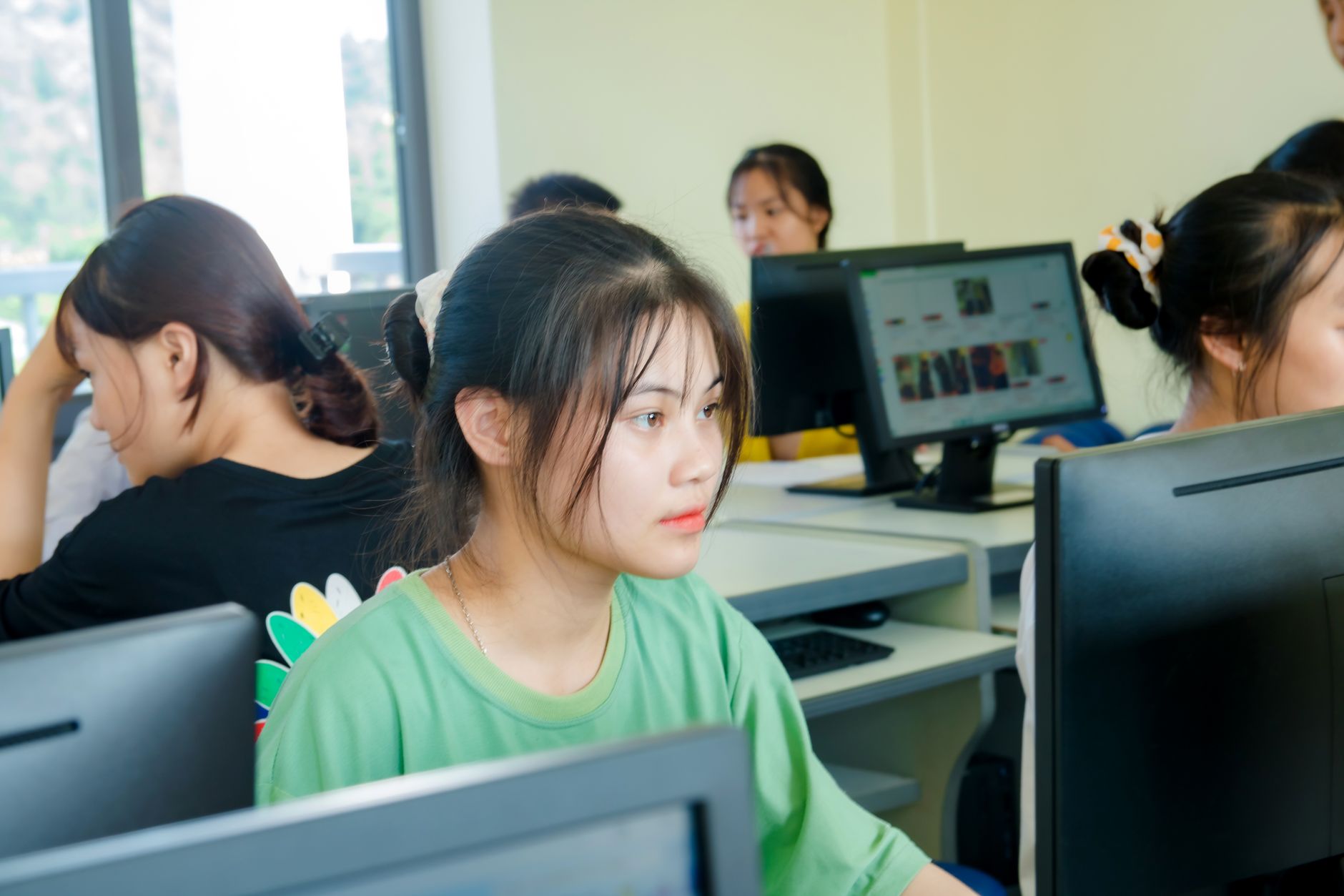 Qualifi Level 4 Diploma in IT – Web Design — Asian students focused on studying technology in a bright computer classroom setting.