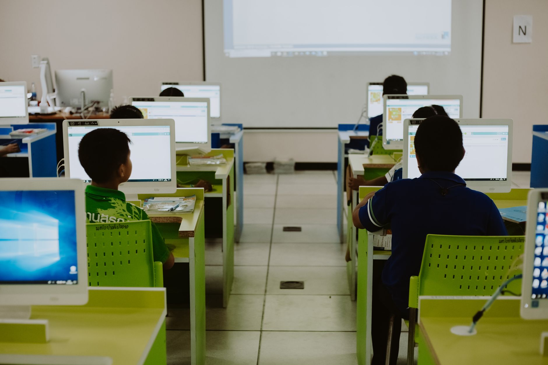 Qualifi Level 4 Diploma in IT – E-commerce — Children focus on computers in a modern classroom setting.