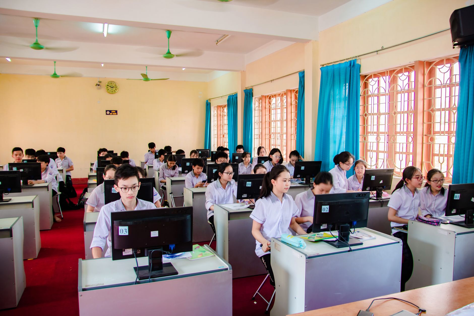 Qualifi Level 5 Diploma in Information Technology — Asian students in uniform learning in a computer lab, focused on their tasks.