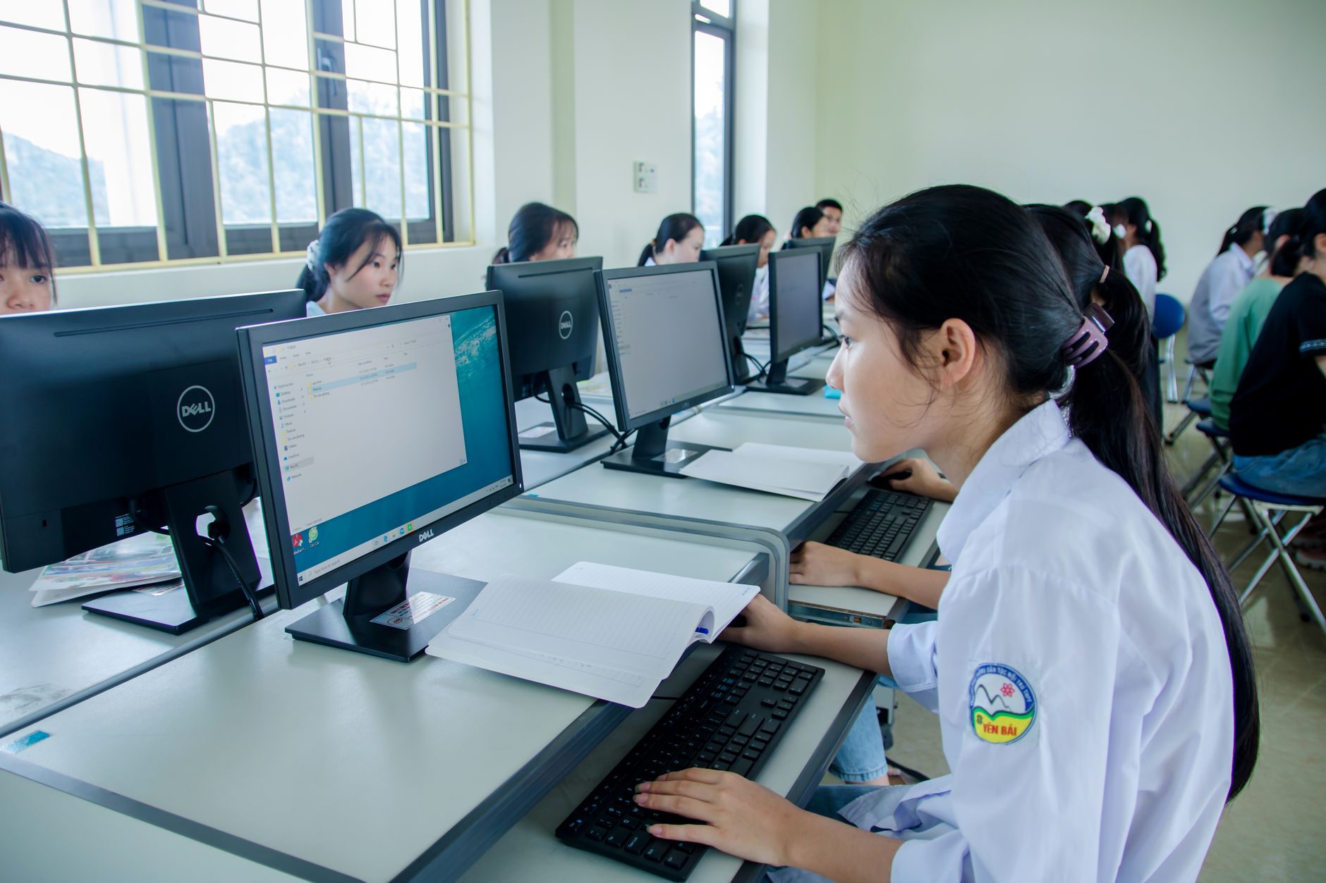 Qualifi Level 5 Extended Diploma in Information Technology — Group of Asian students working together in a computer lab focused on teamwork and technology.