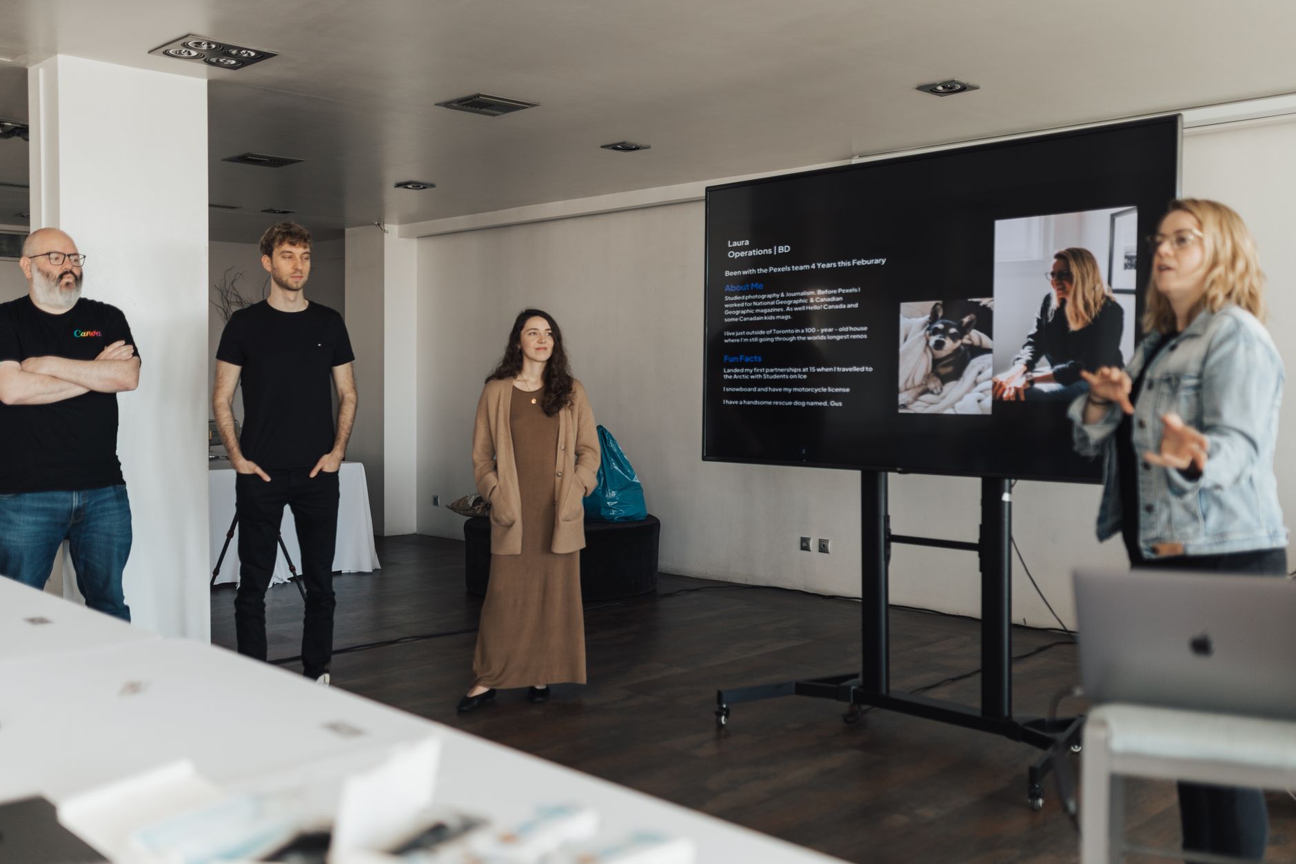Business Resources — Team gathers around a digital presentation in a modern office setting.
