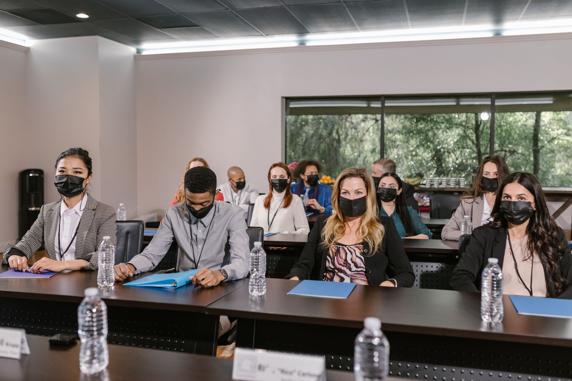 Understanding Health and Safety in the Business Workplace — A group of masked professionals in a business meeting setting, maintaining social distance.