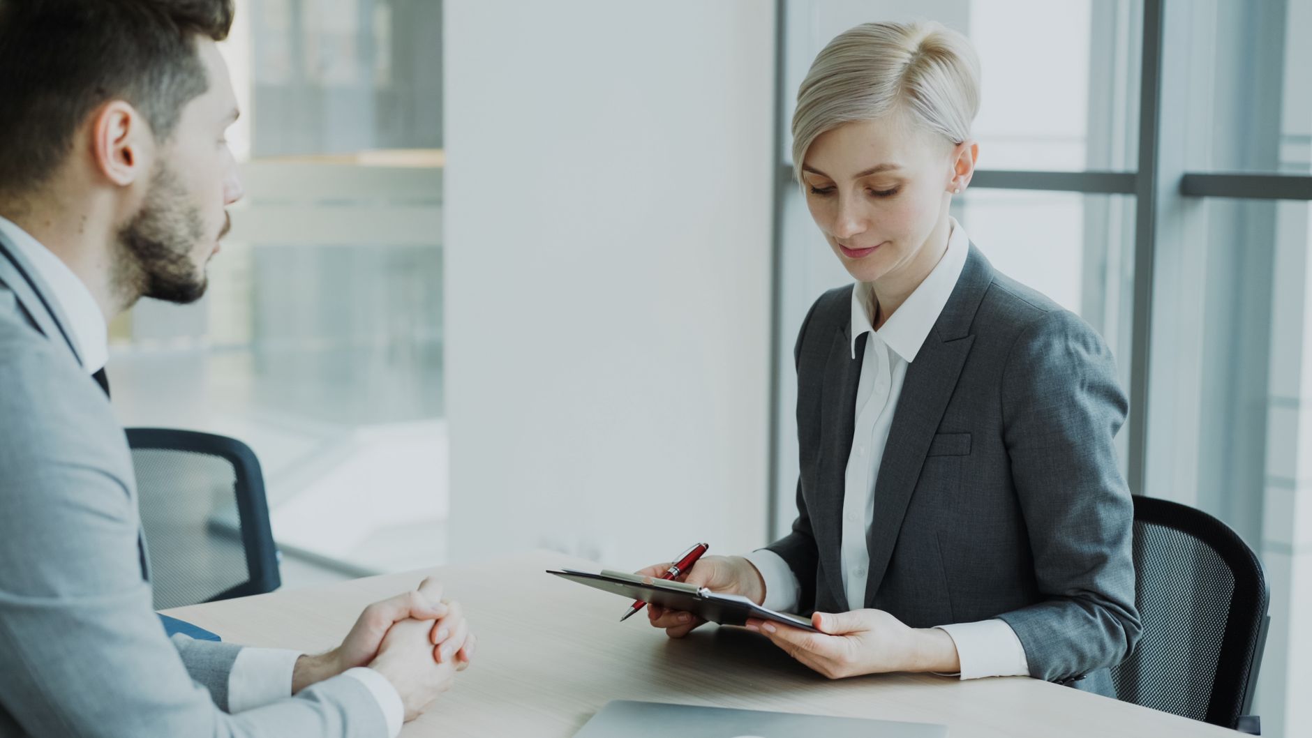 Recruitment and Selection in Business — Two professionals in a modern office discussing business. Bright, professional setting.