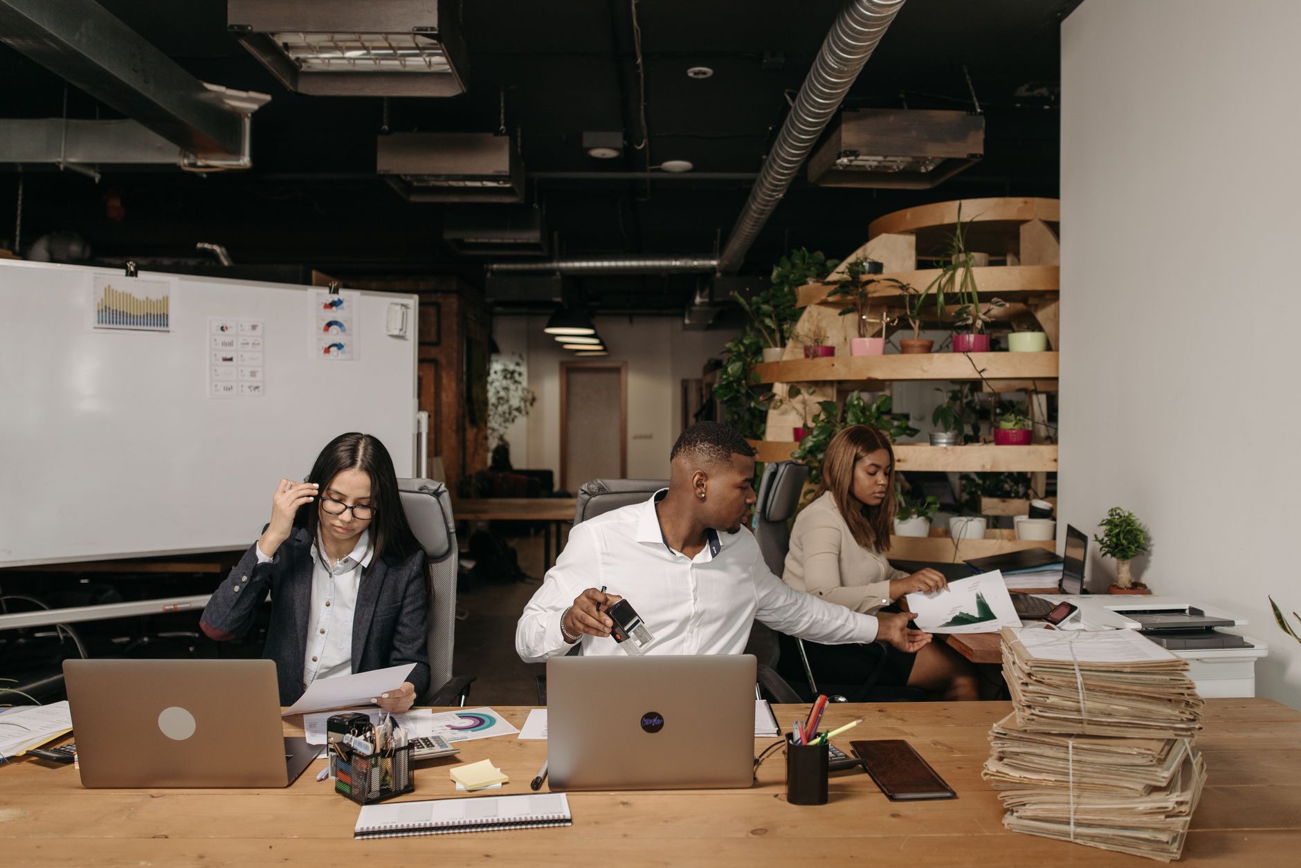Managing Business Operations — Diverse team collaborating in a modern office setting with laptops and documents.