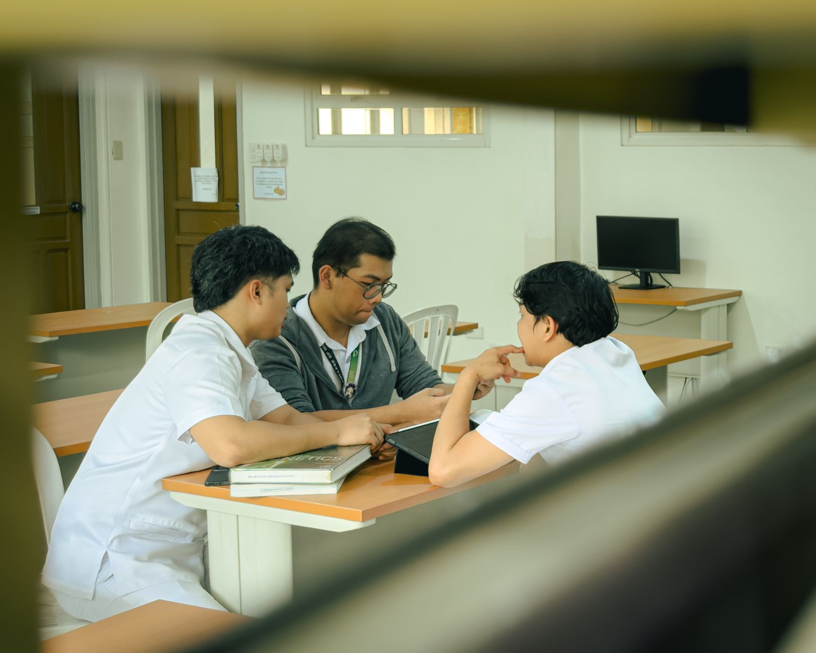 Working in Teams — Three students collaborating on a project inside a classroom, fostering teamwork and learning.