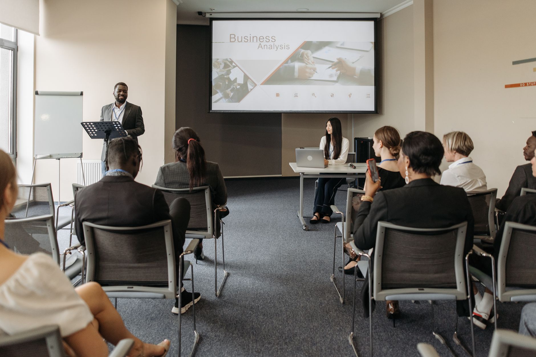 Organisational Culture — A diverse group of adults attending a presentation in a conference room setting.