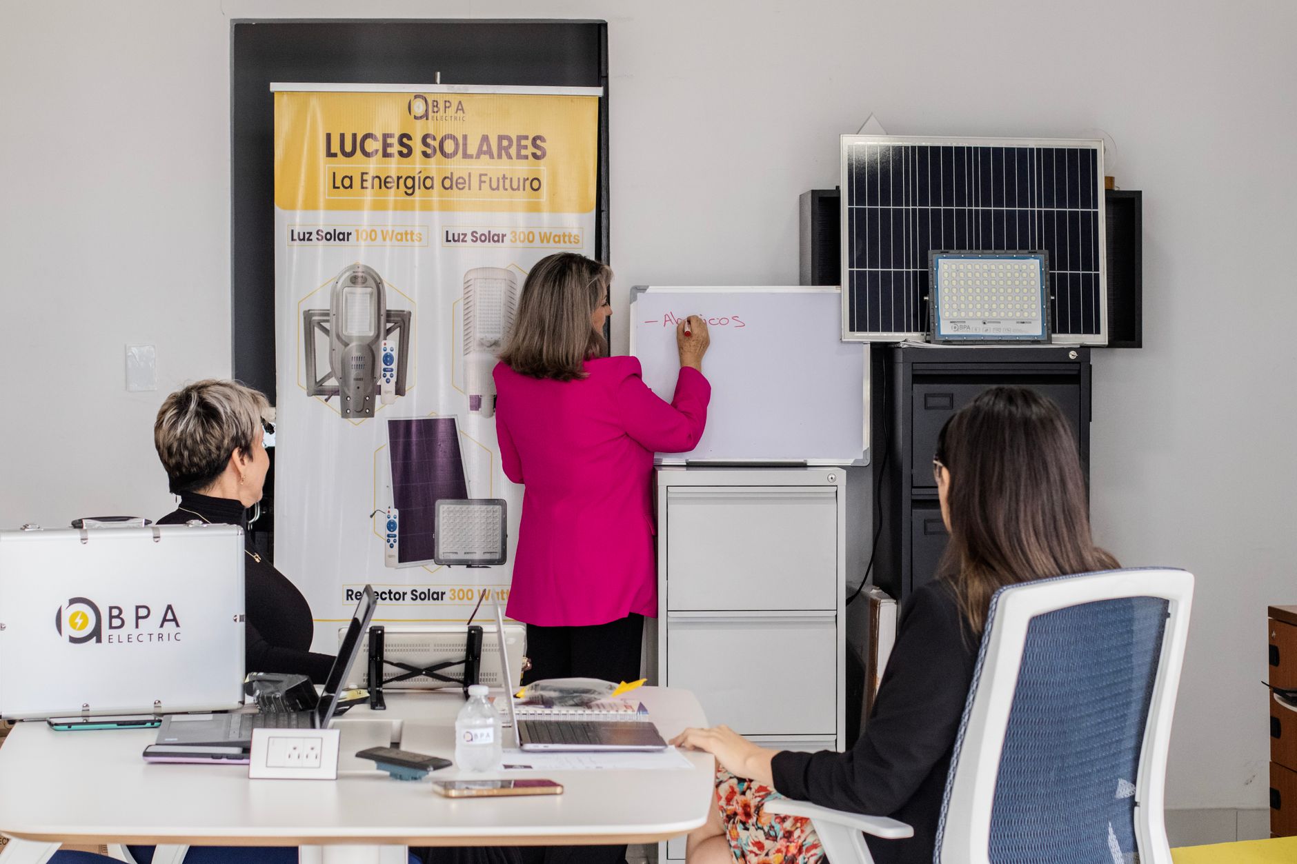 Business Resources — A team engaged in brainstorming solar energy solutions with panels and a whiteboard in an office.