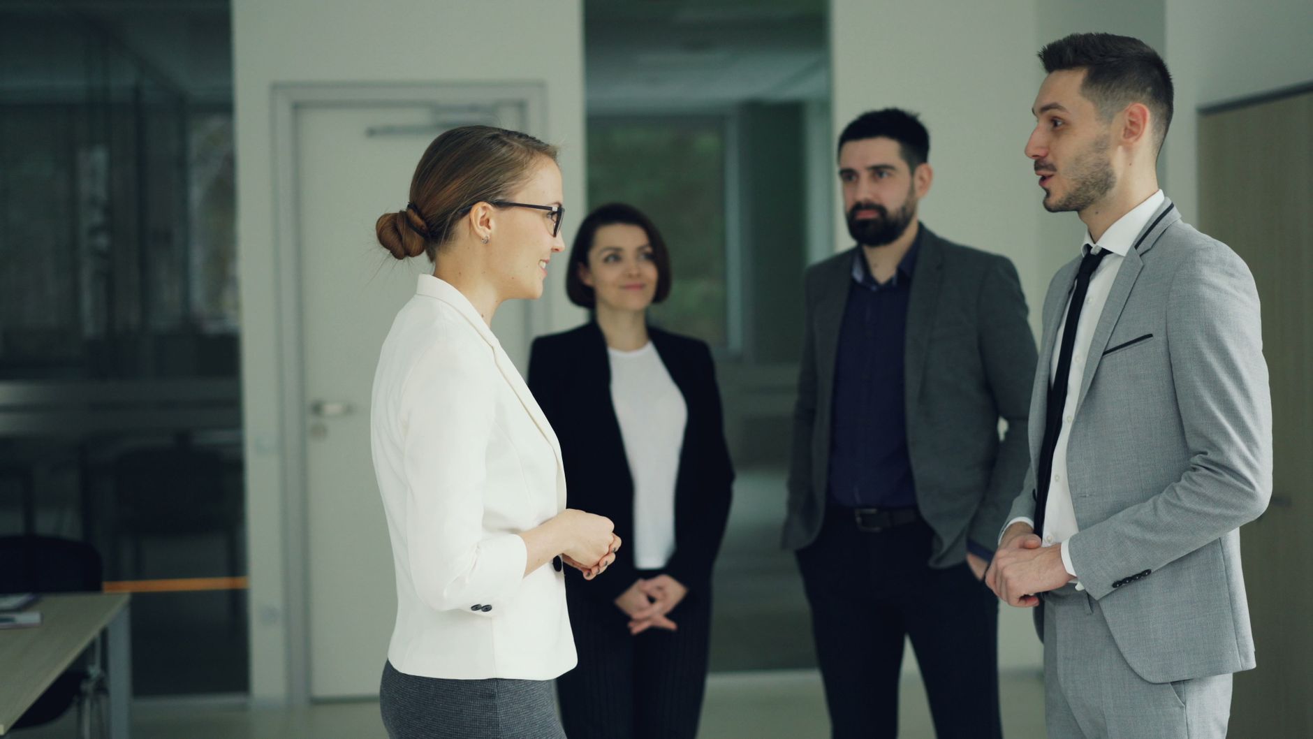 Human Resource Management — Group of professionals in formal attire having a discussion in a modern office setting.