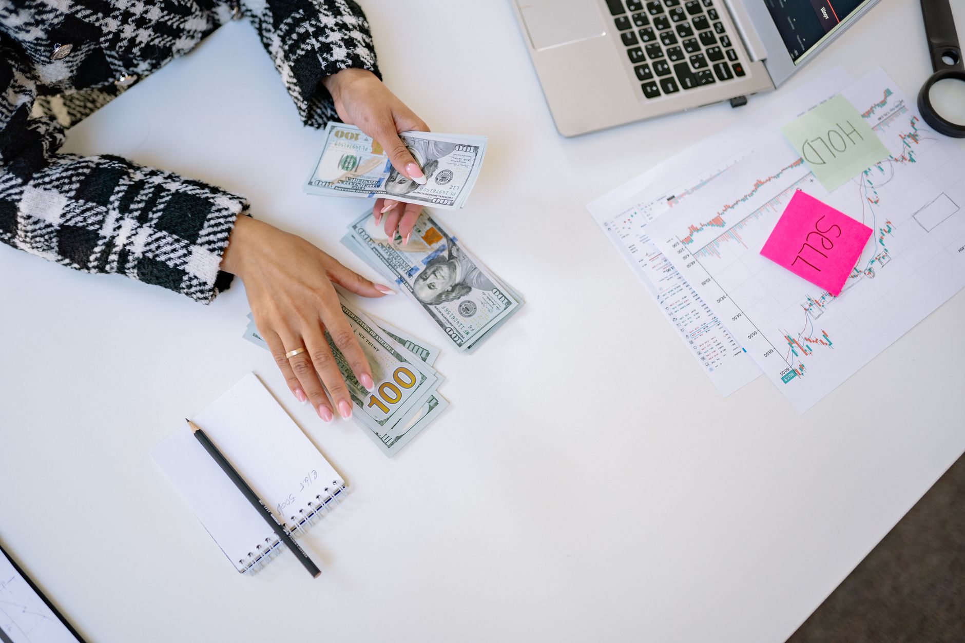 An Introduction to Finance — Businesswoman counting dollar bills with financial charts and laptop on table. Investment and finance concept.