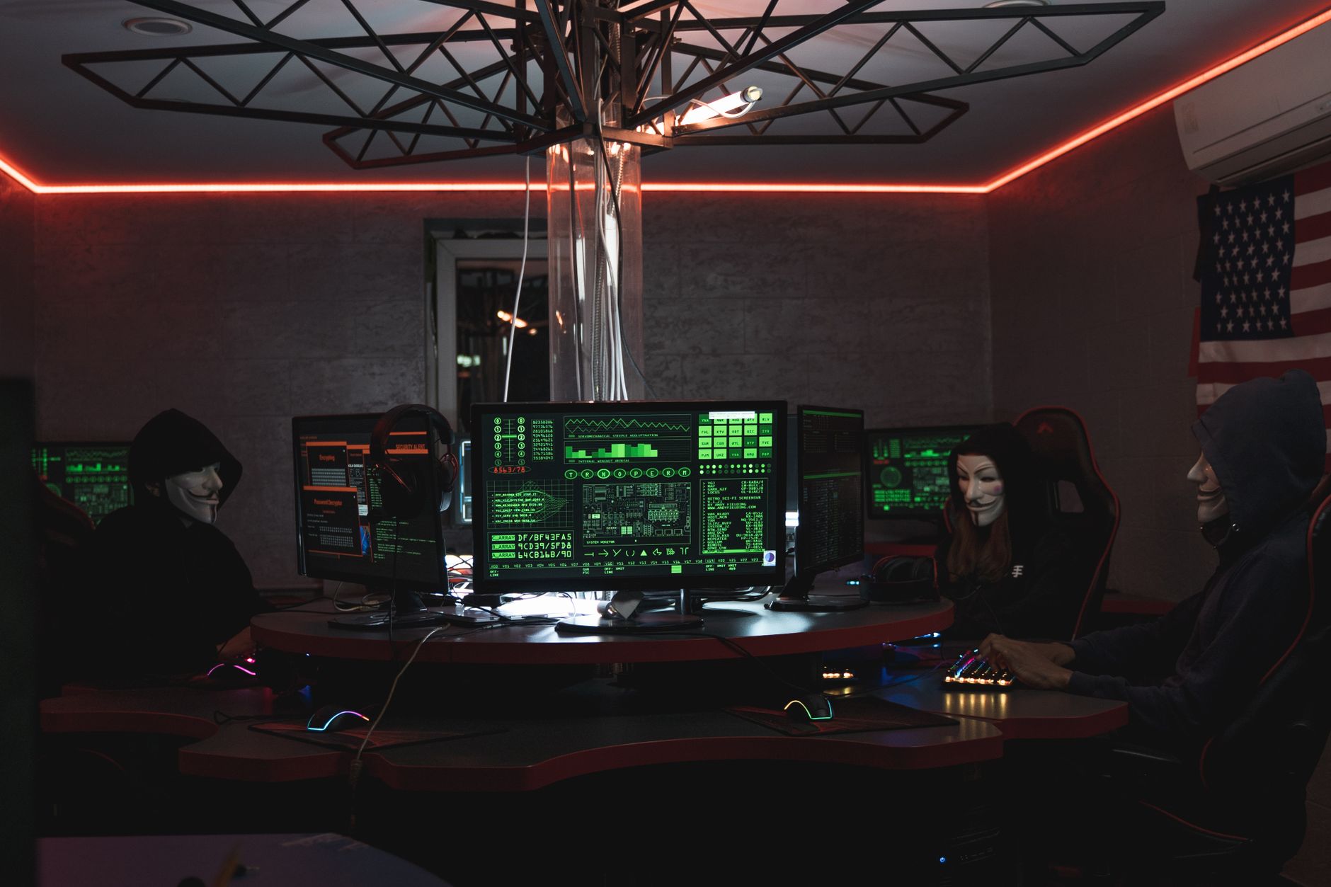 Cyber Security — Team of hackers with Guy Fawkes masks coding in a dark room with computers.