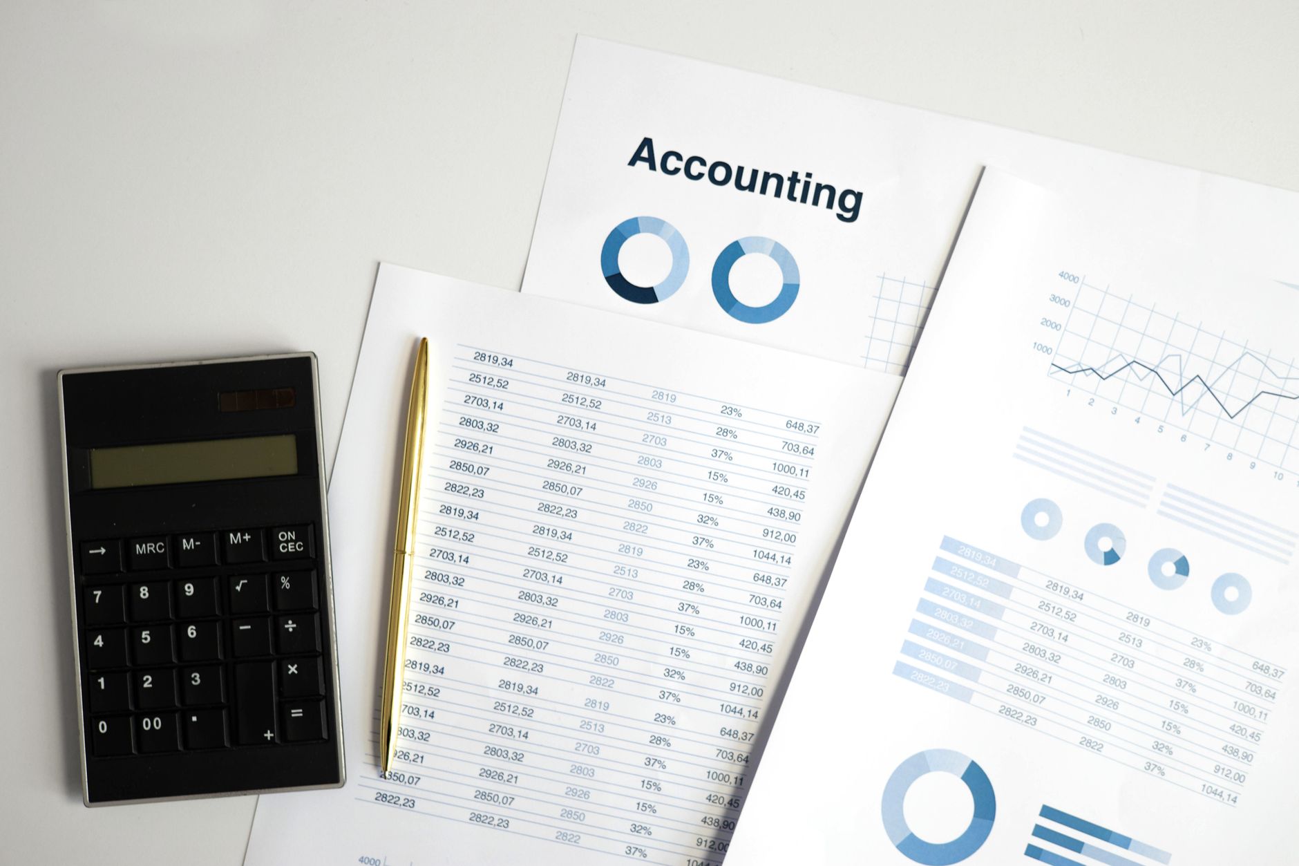 Entrepreneurial Finance and Accounting — Calculator and accounting documents with charts on a workspace.