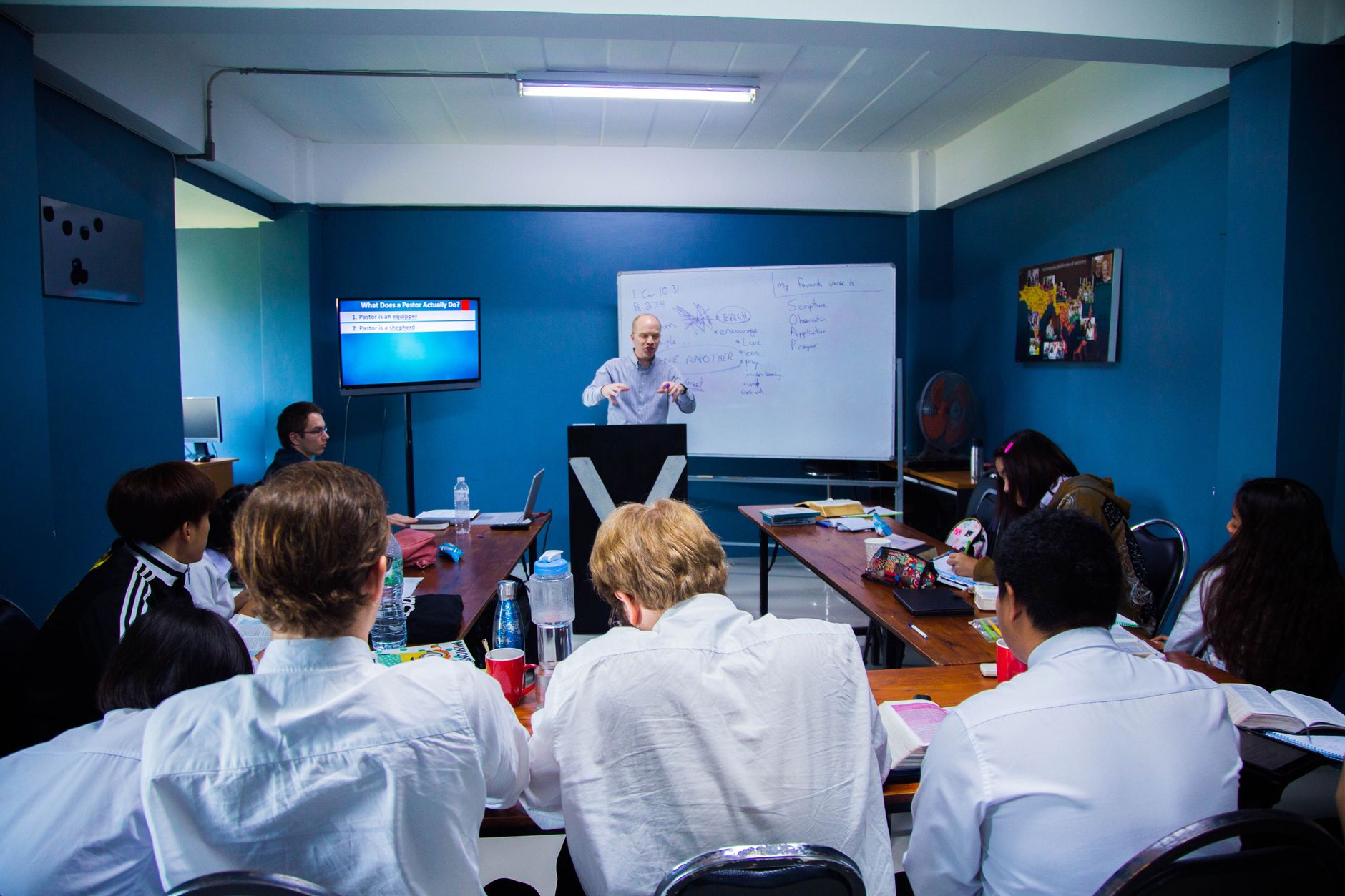 Developing Teams — A business seminar with people attentively listening to a speaker in a modern classroom setting.