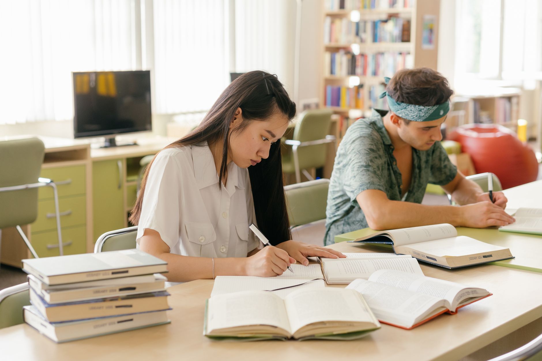 Communication and Cultural Skills for University — College students studying and taking notes in a library setting.