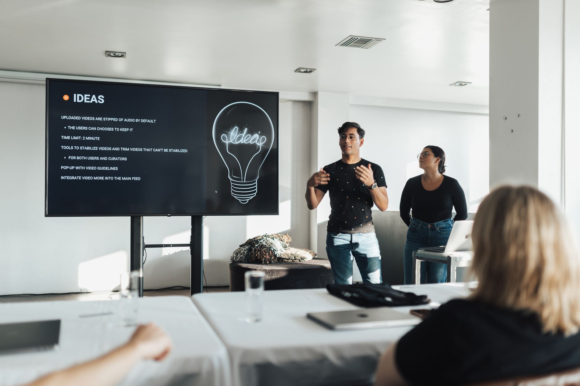Thinking Entrepreneurially — Two colleagues giving a dynamic business presentation in a modern office environment, engaging their audience.