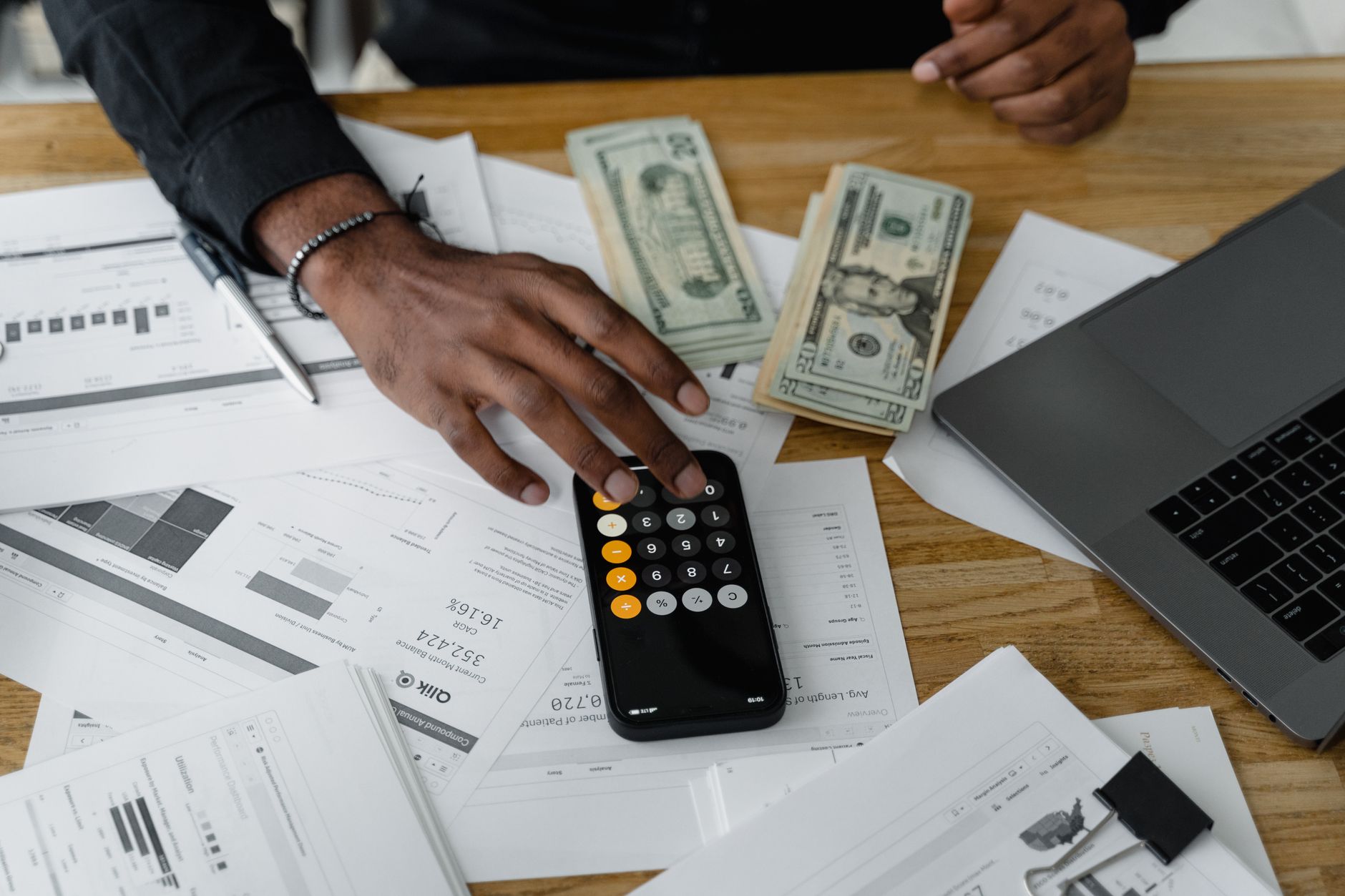 Managing and Using Finance — Overhead view of financial documents with calculator, cash, and laptop for financial planning.