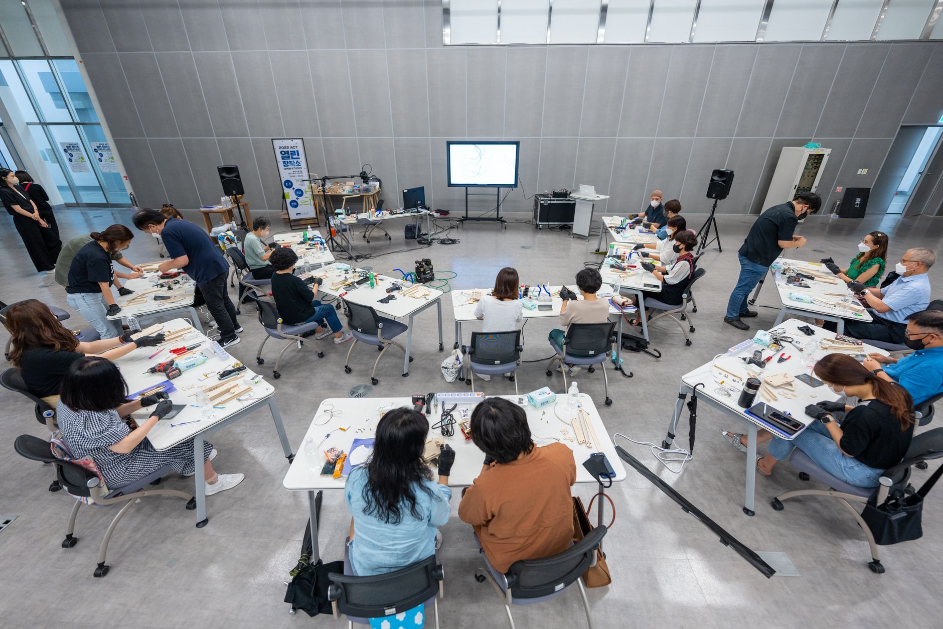 The Innovative Mind-set — Overhead view of a hands-on classroom workshop with diverse students using hi-tech equipment.