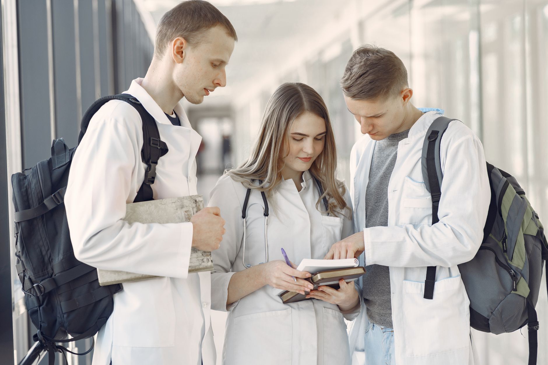 Qualifi Level 7 Diploma in Hospitality and Tourism Management — Three medical students in a hallway discussing notes, fostering teamwork and learning.