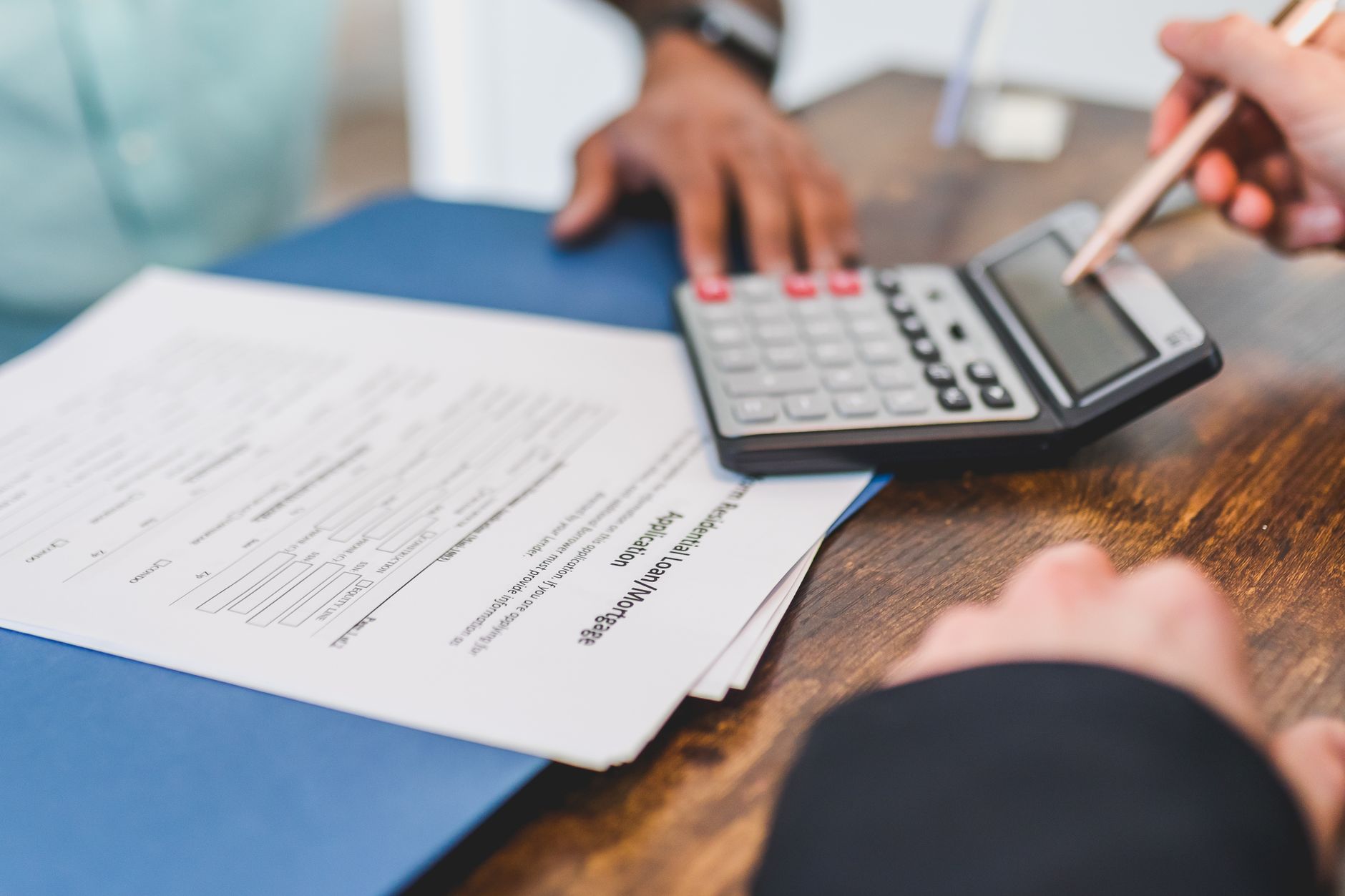 Qualifi Level 7 Diploma in Accounting and Finance — Hands using a calculator with real estate documents on a desk, indicating a financial transaction or meeting.