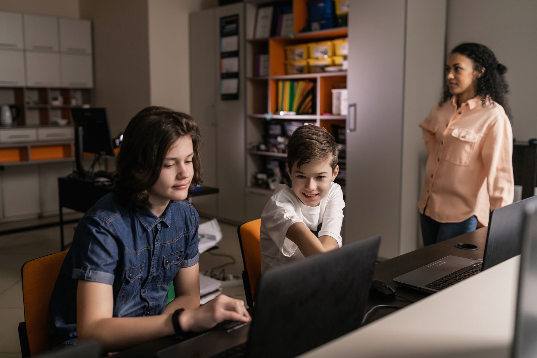Qualifi Level 5 Diploma in IT – E-commerce — Students using laptops in a classroom setting with a teacher supervising, promoting digital education.
