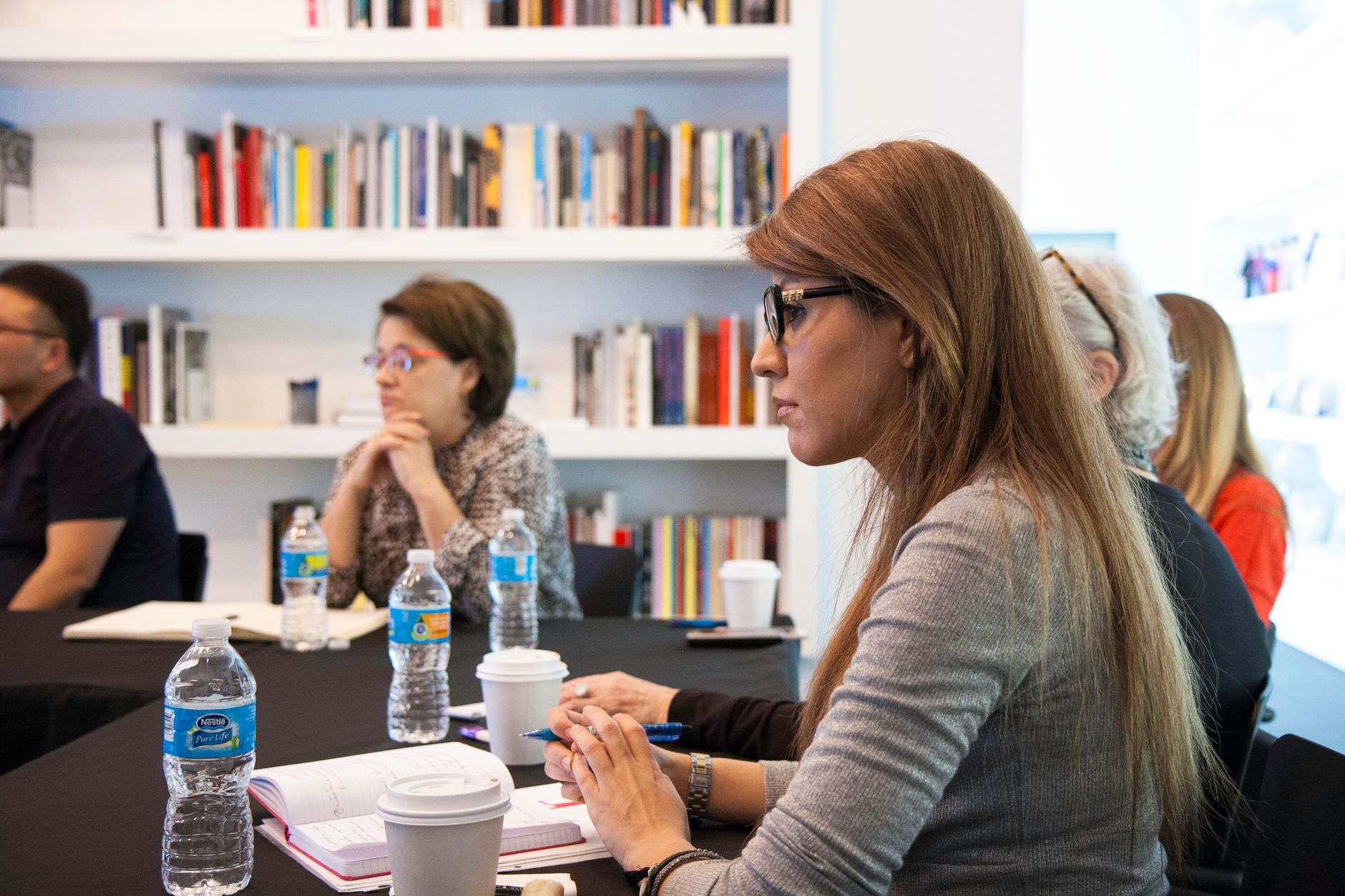 Business Communication — Business professionals meeting in modern office with bookshelves. Collaborative and focused environment.