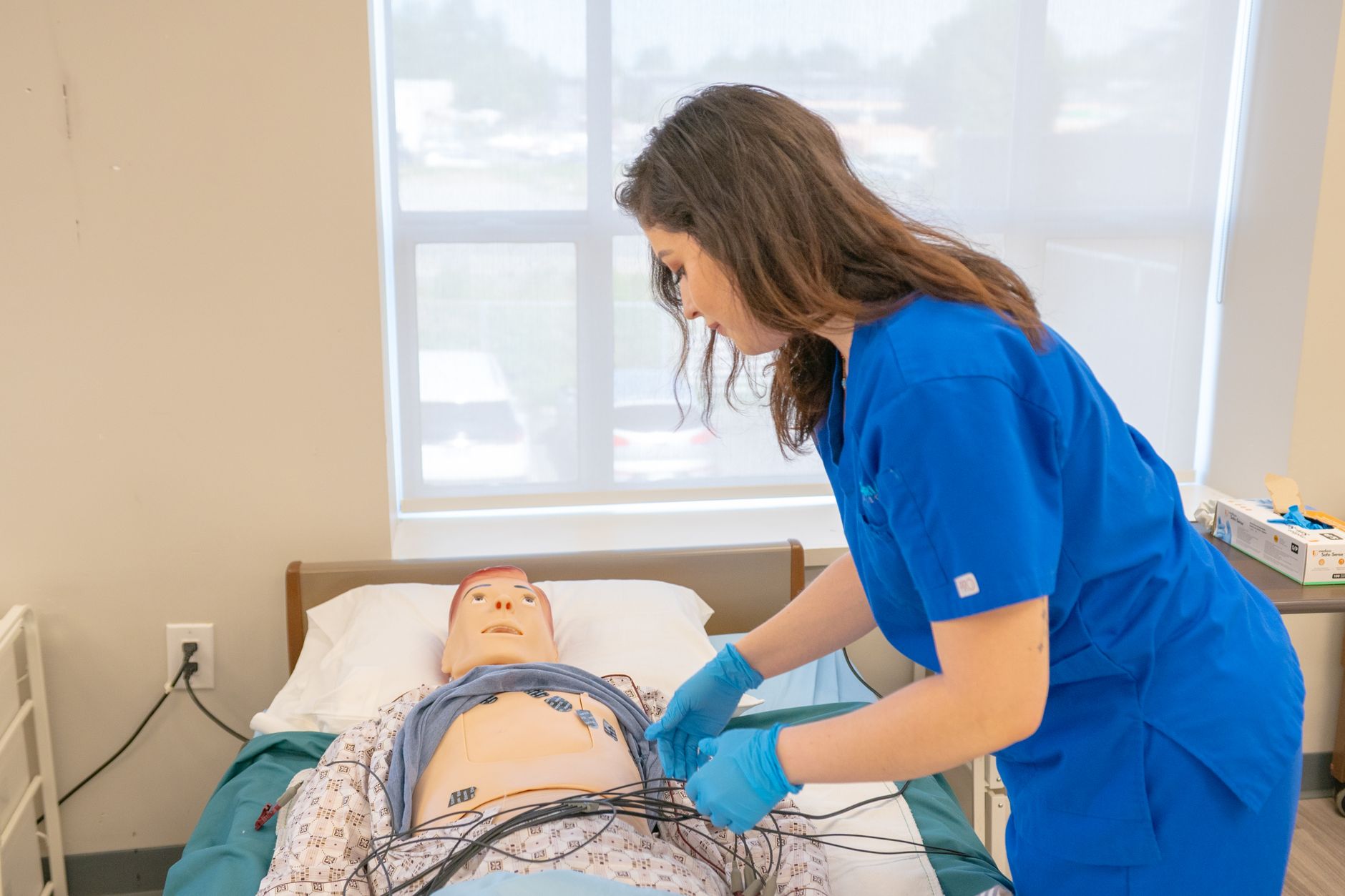Social Enterprise and Third Sector Organisations — Nursing student practicing medical procedures on a mannequin in a clinical lab setting.