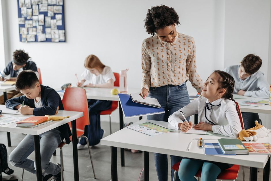 Qualifi Level 5 Certificate in Teaching English as a Foreign Language with Practice (CertTEFL) (The TEFL Academy) — A diverse group of students engaged in learning with a teacher's guidance in a classroom setting.