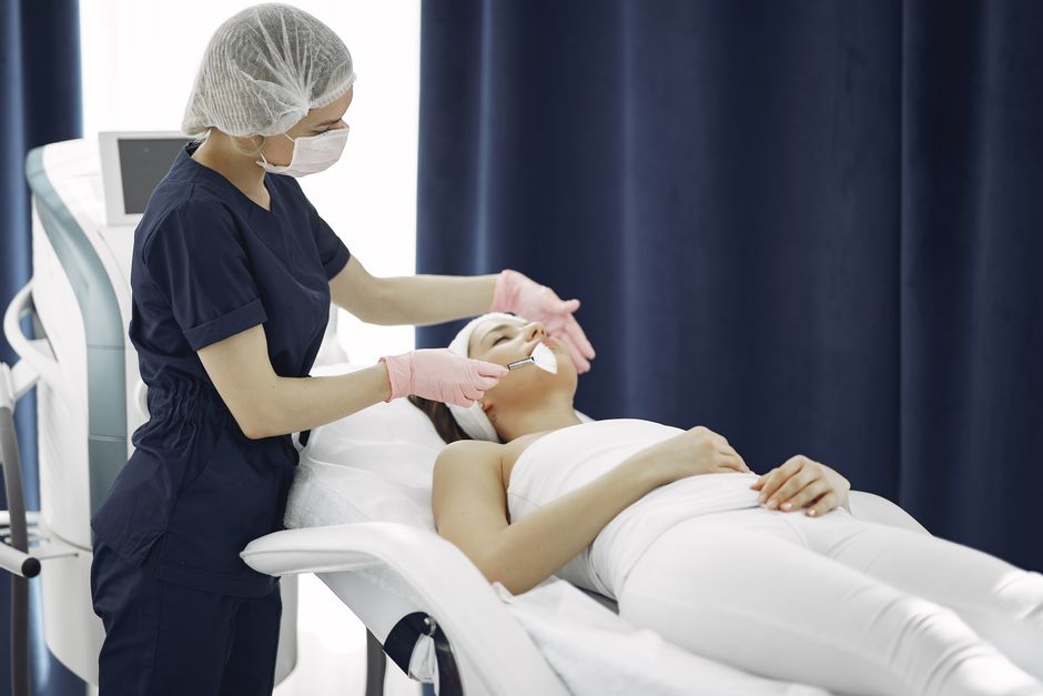 Qualifi Level 4 Certificate in Plasma Skin Rejuvenation — Aesthetician applying facial treatment on a relaxed woman in a modern spa clinic setting.