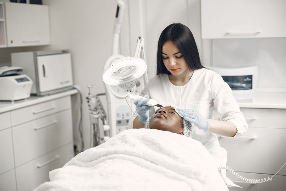 Qualifi Level 4 Certificate in Aesthetic Practice — Aesthetician providing a rejuvenating facial treatment to a client in a modern spa clinic setup.