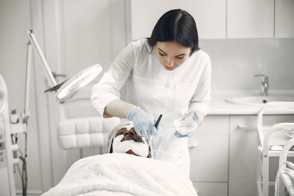 Qualifi Level 5 Diploma in Aesthetic Practice — Woman provides facial treatment to patient in a spa setting, ensuring relaxation and care.