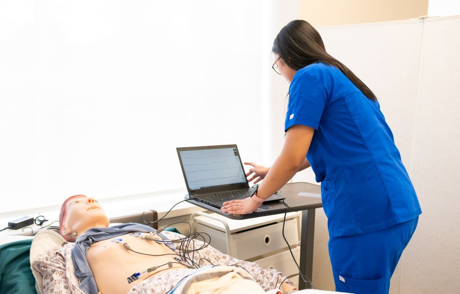 Qualifi Level 5 Certificate in Human Nutrition and Gut Microbiome — Nurse in training using a laptop with a medical dummy in a clinical simulation lab.