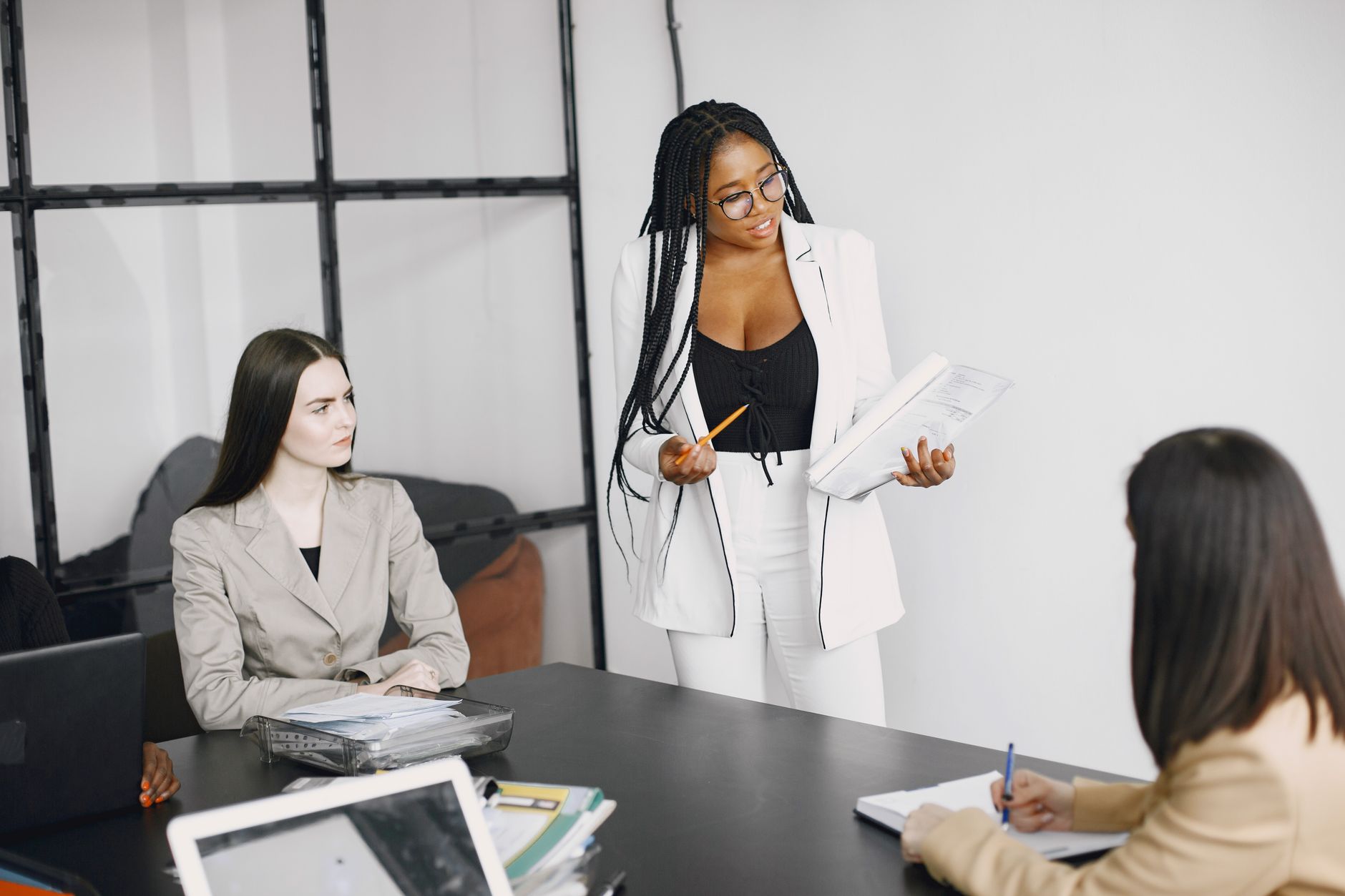 Effective Decision Making — A diverse team of women engaged in a collaborative business meeting in a modern office setting.