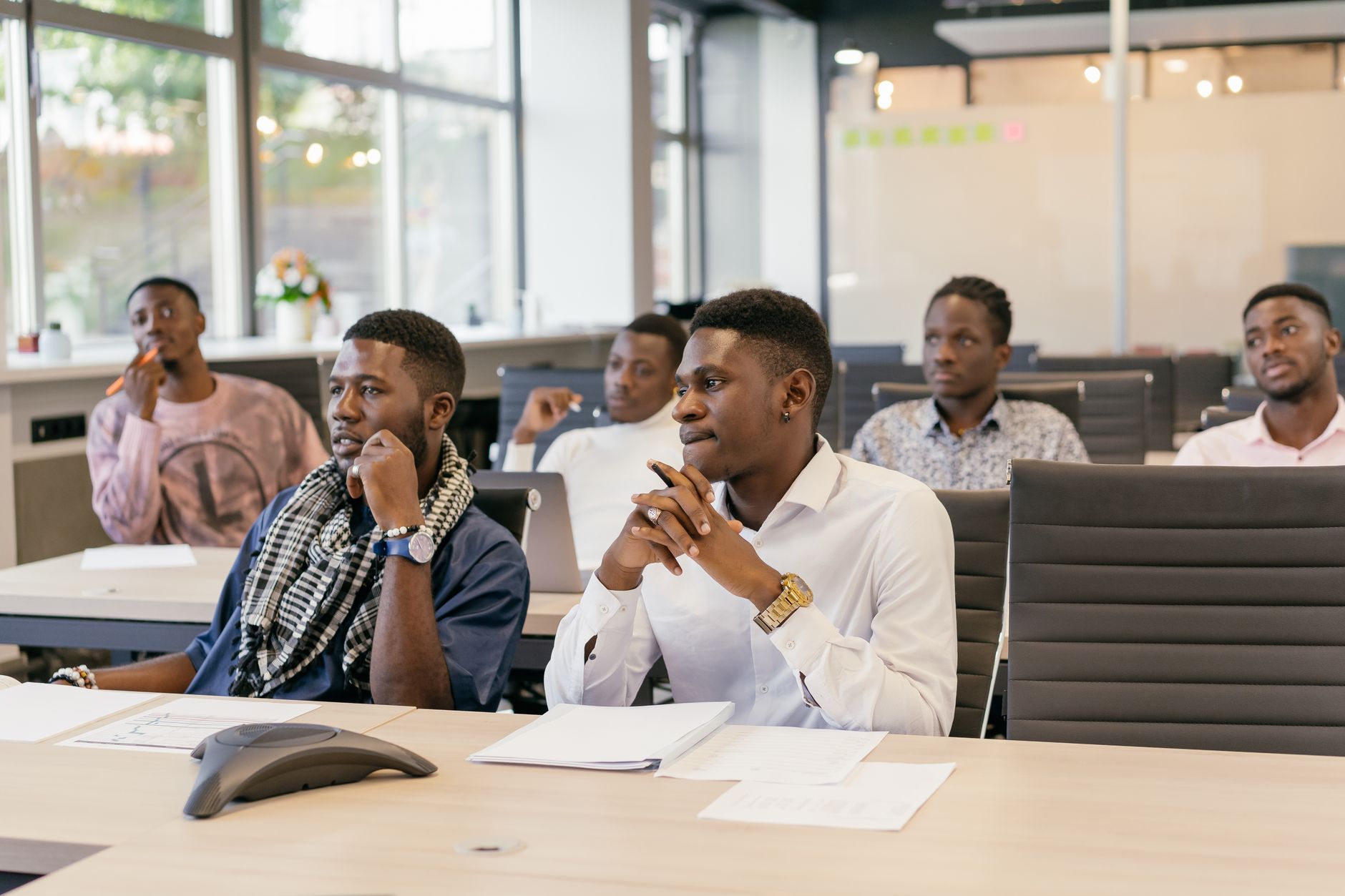 Business Development — A group of men attentively participating in an office meeting, displaying teamwork and collaboration.