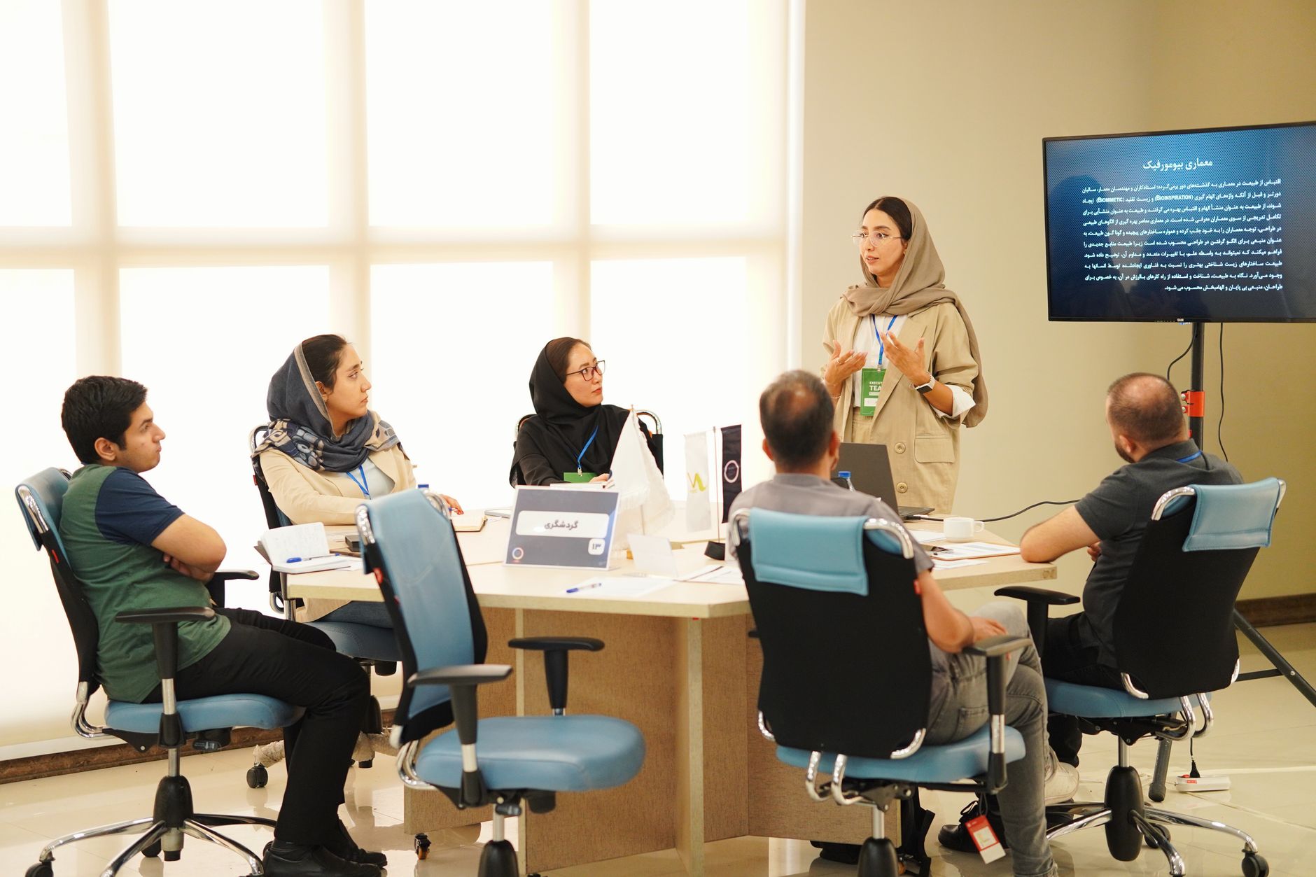 Business Models and Growing Organisations — Group of professionals collaborating in an office meeting with presentations.