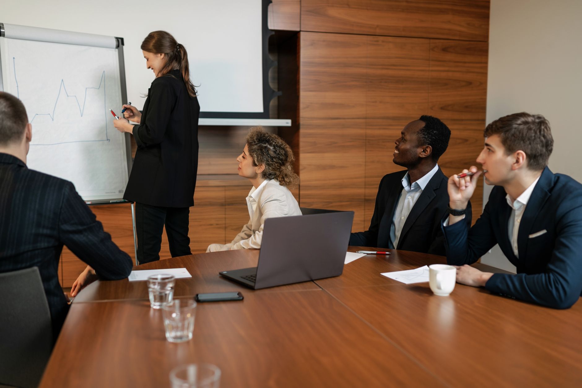 Managing Change — Group of professionals engaged in a presentation during a team meeting in a modern office setting.