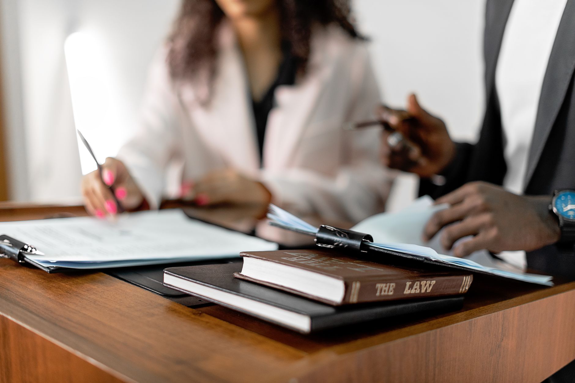 Procurement Risk and Contract Management — Two lawyers reviewing documents with law books on a desk. professional legal environment.