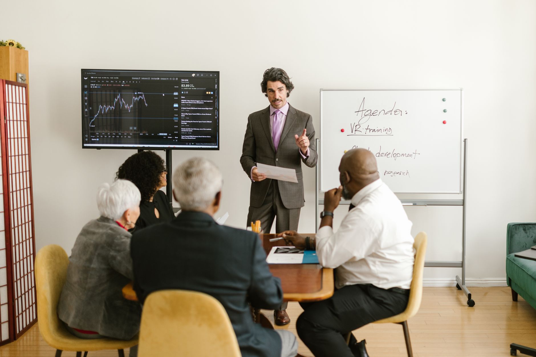 Development as a Strategic Manager — A corporate professional presents market data during a team meeting in an office setting.