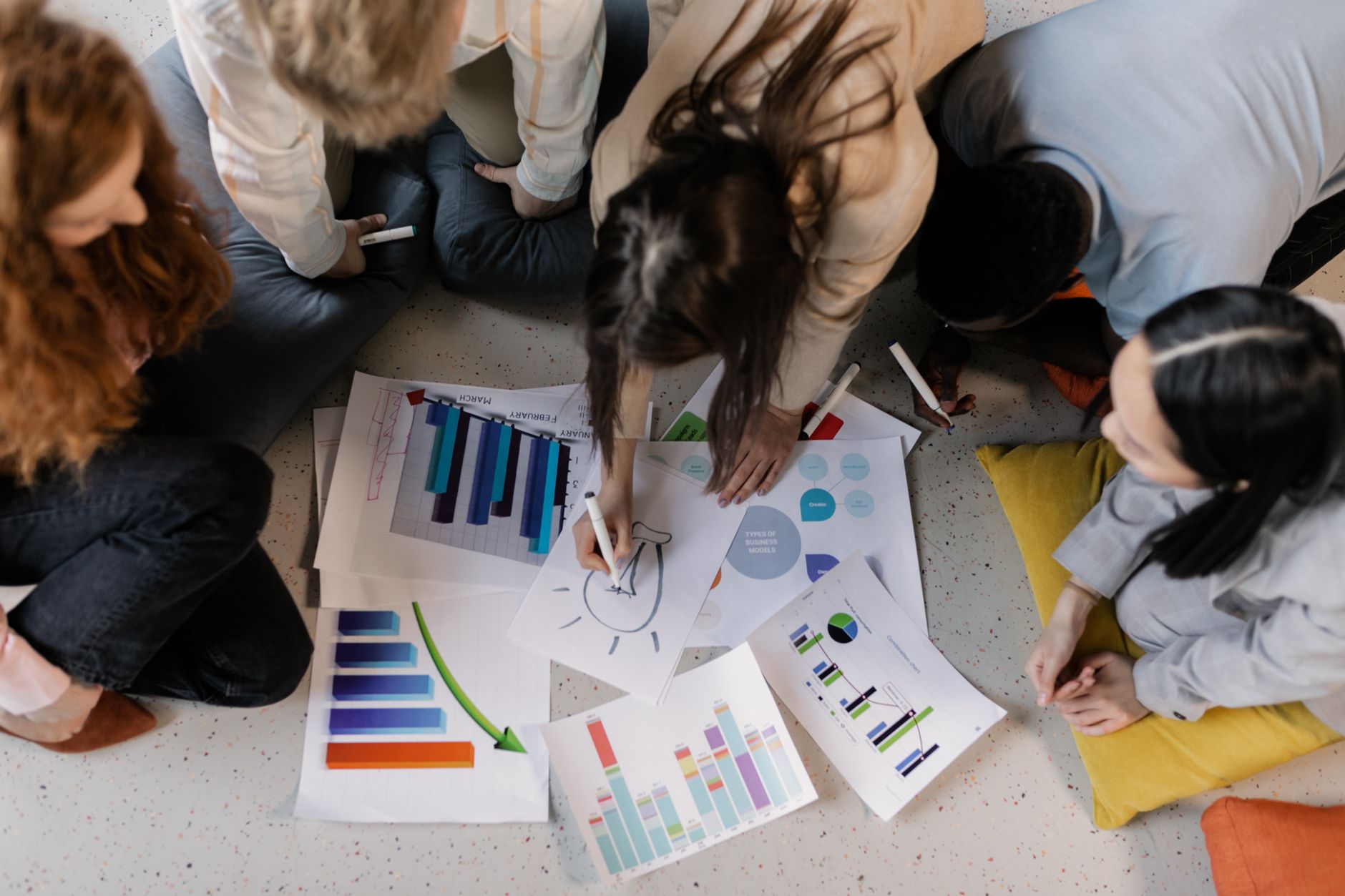 Strategic Marketing — Overhead view of diverse team brainstorming on business strategy using charts and graphs.