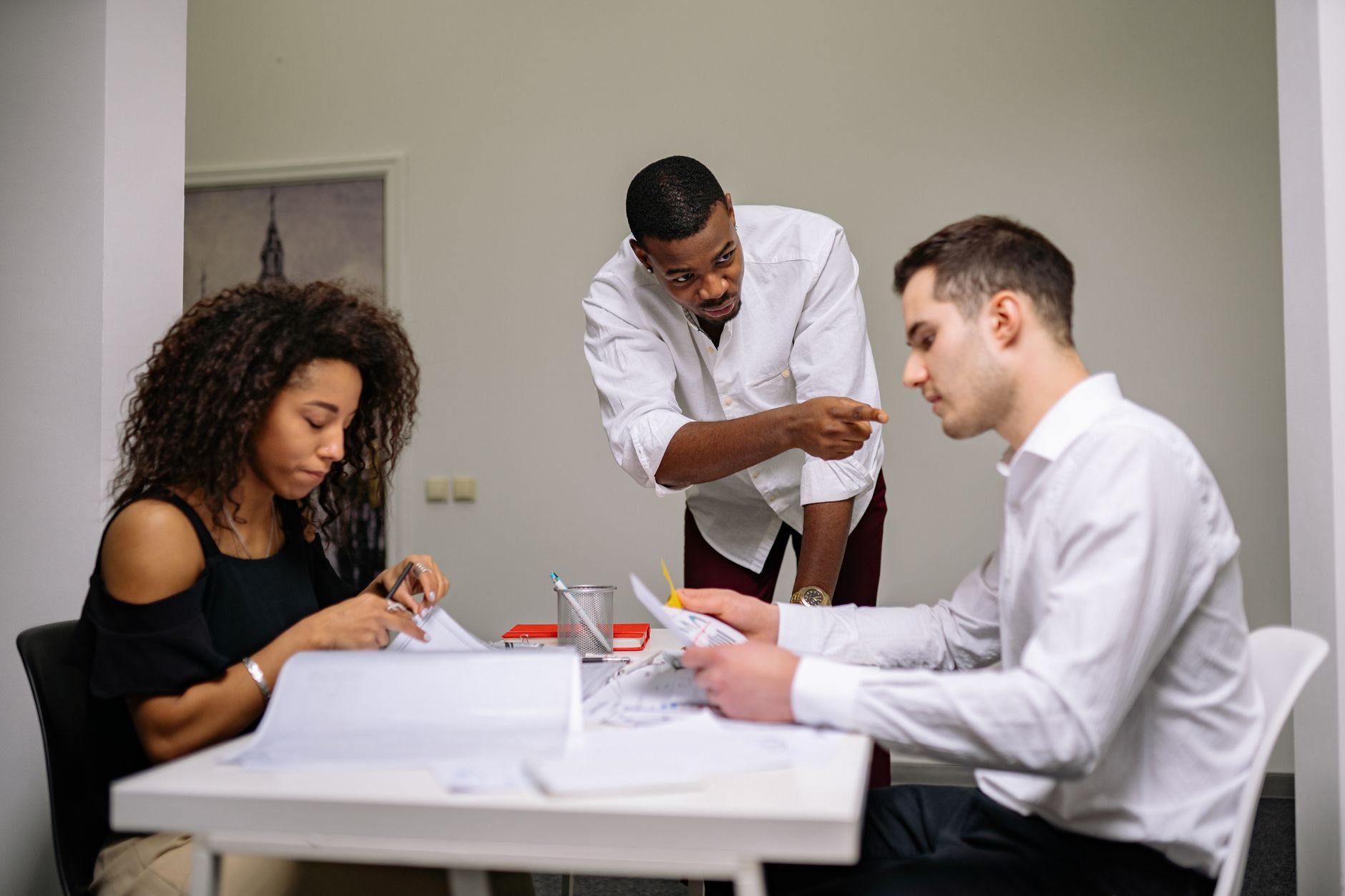 Responsible Leadership and Governance — Manager instructing employees during a focused team meeting in a modern office setting.